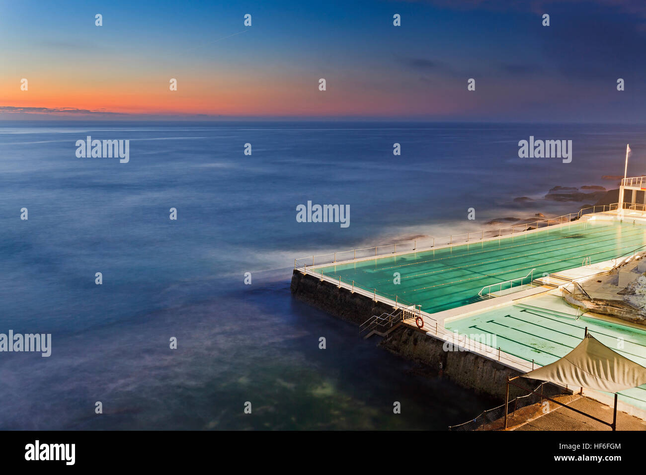 Sunrise oltre oceano pacifico orizzonte a Bondi Beach a Sydney. Nuoto rock pool undernear aperto al pubblico a Bondi Pavilion Foto Stock