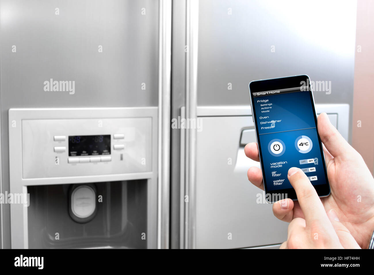 Uomo usa il suo smartphone per impostare il frigo Foto Stock