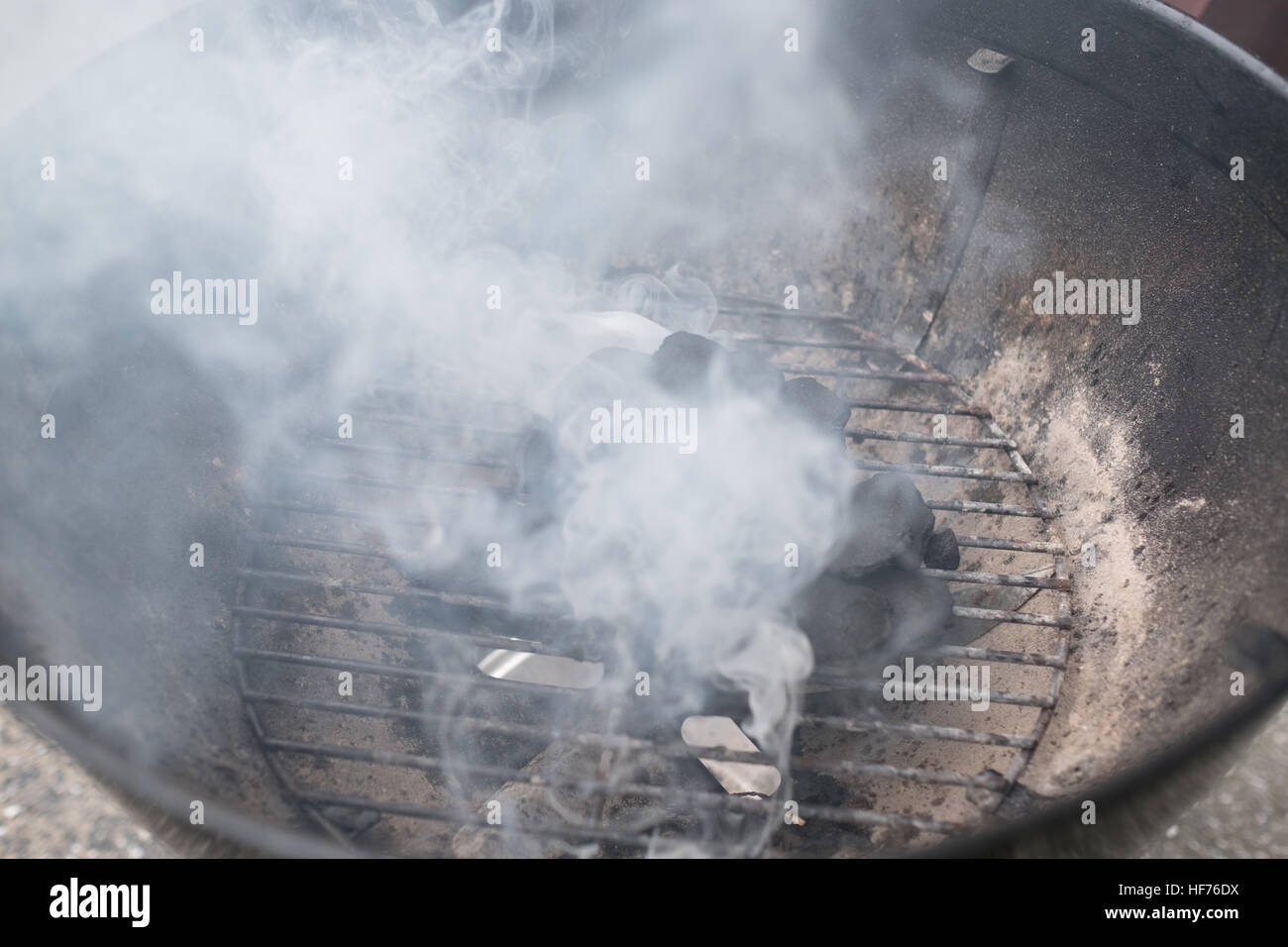 Fumo proveniente al di fuori della griglia con bricchetta, primo piano Foto Stock