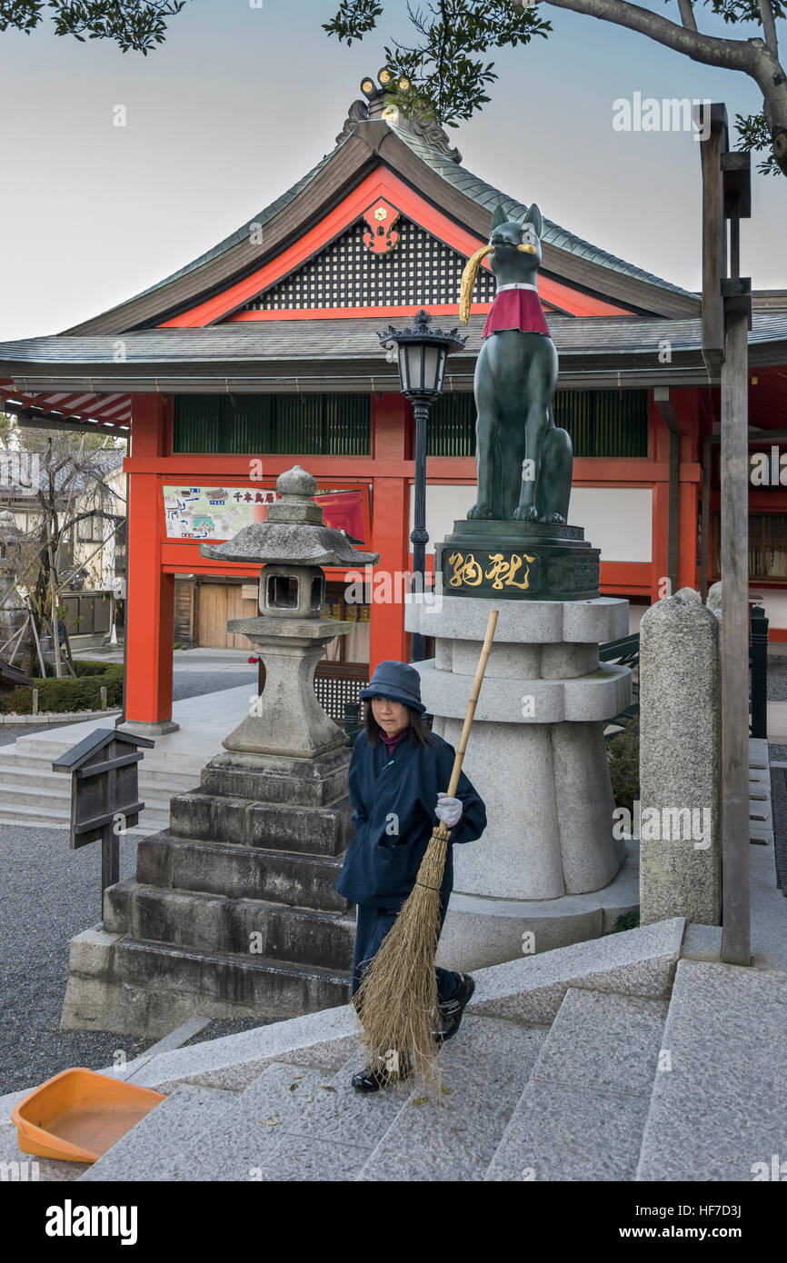 Donna ampie scale accanto a Kitsune (Fox) statua con levetta di riso, Gai-haiden, Fushimi Inari Taisha Sacrario Scintoista, Kyoto, Giappone Foto Stock
