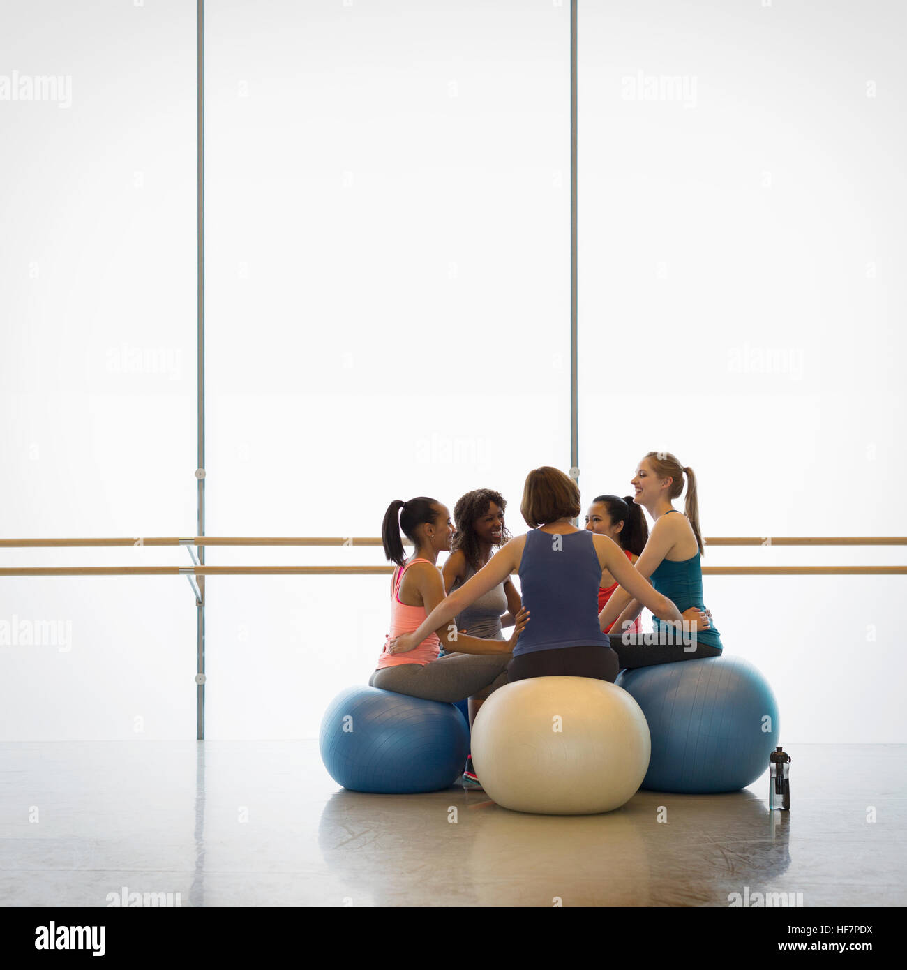 Le donne su sfere fitness collegato in circolo nella classe di esercizio palestra studio Foto Stock
