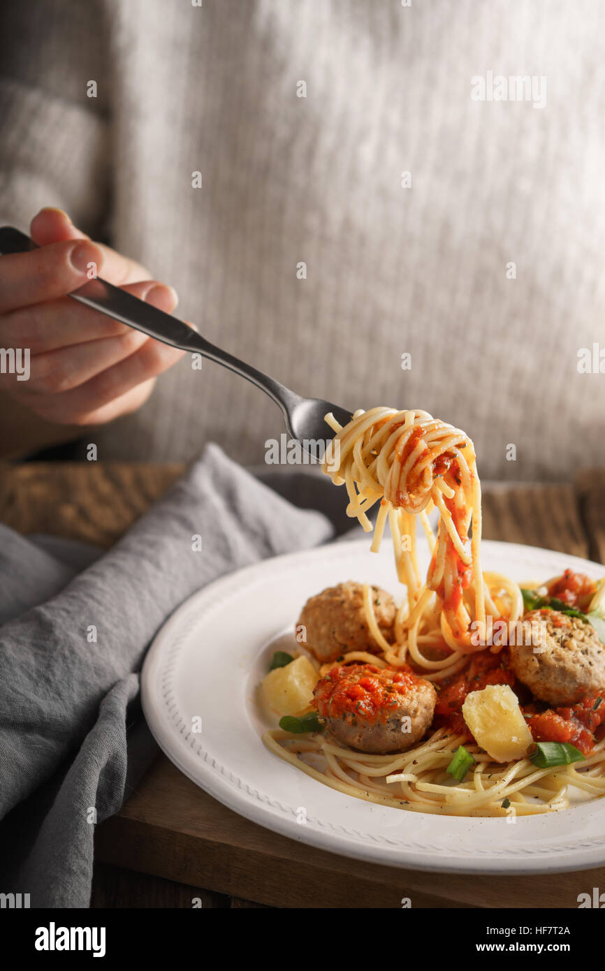 Donna mangiare spaghetti con le polpette di carne e formaggio in verticale Foto Stock
