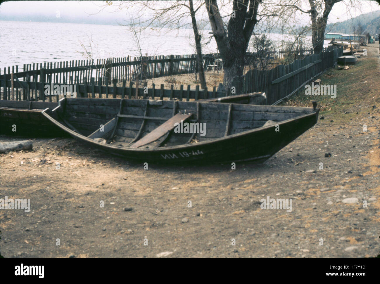 Una barca di legno galleggiante sul lago Baikal, situato nella Siberia orientale, conosciuta per le sue acque profonde e limpide e la bellezza naturale. Questa immagine cattura la semplicità della barca tra il vasto lago e il paesaggio circostante. Foto Stock