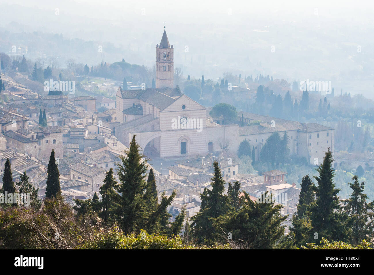 Assisi nella nebbia e la Basilica di Santa Chiara (Santa Chiara), la provincia di Perugia, Regione Umbria, Italia. Foto Stock