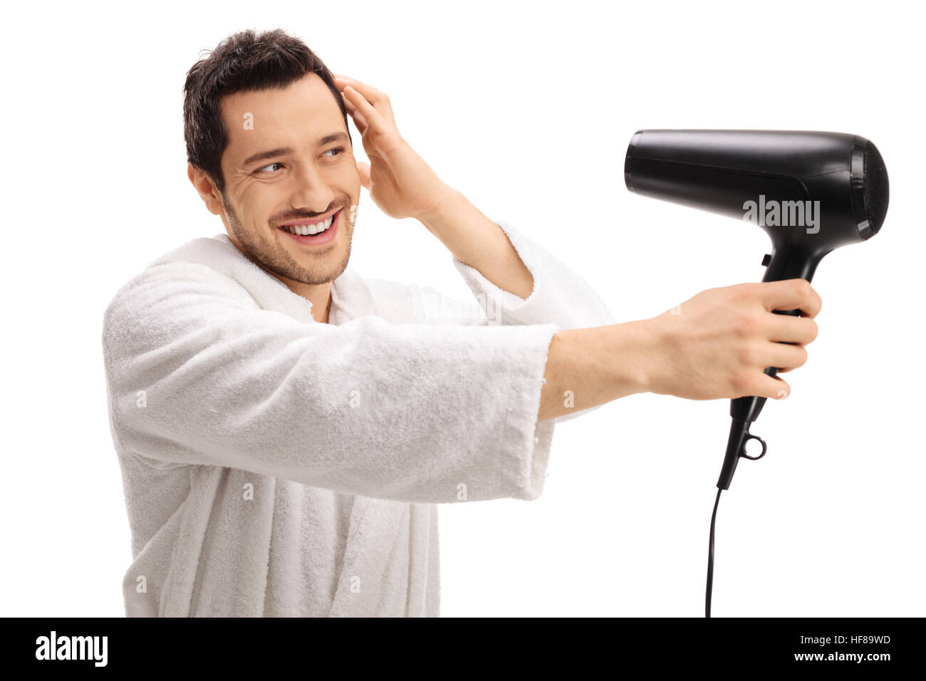 Giovane ragazzo in un accappatoio asciugando i capelli con un asciugacapelli isolati su sfondo bianco Foto Stock