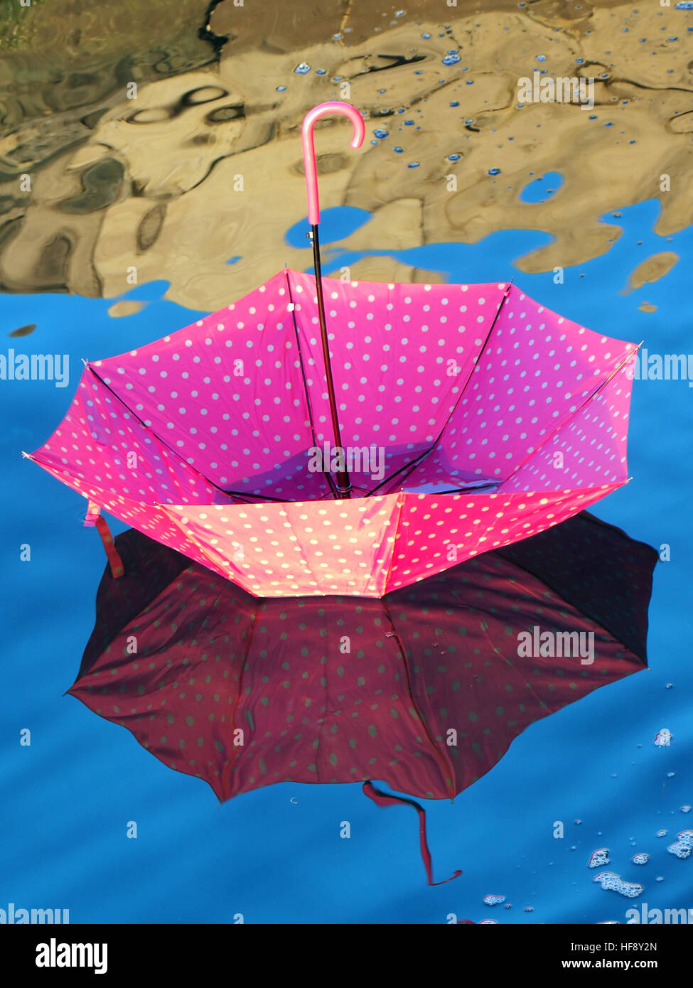 Spoted rosa ombrello capovolta che galleggia sulla superficie dell'acqua Foto Stock