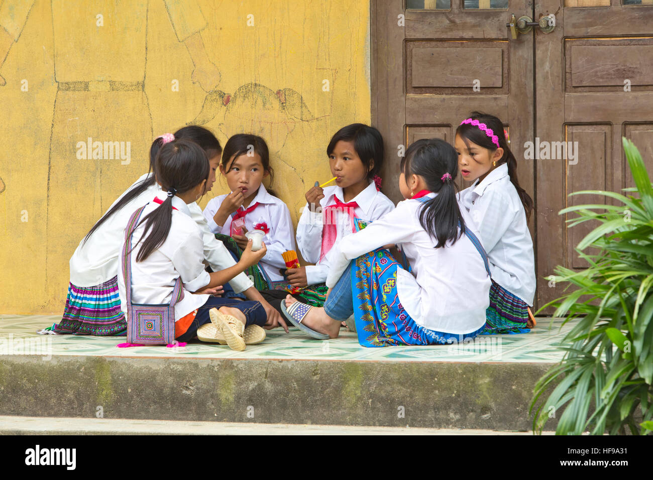 Le giovani ragazze comunicante & gustando uno spuntino durante la pausa scolastica. Foto Stock