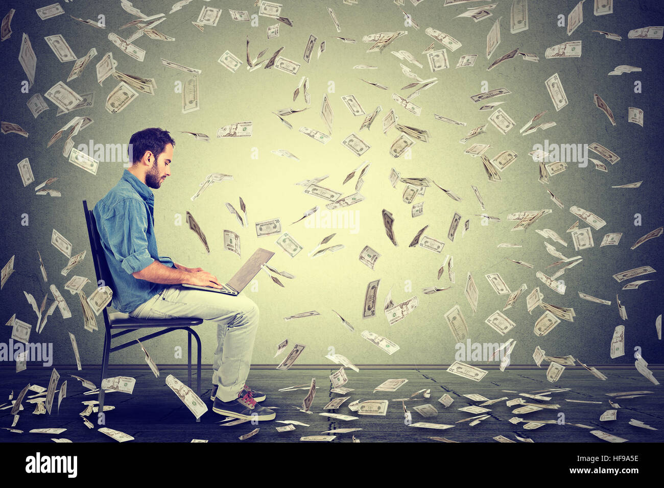 Giovane uomo che utilizza un notebook building online business fare soldi le fatture del dollaro cash cadere verso il basso. Pioggia di denaro principiante è imprenditore economia di successo con Foto Stock