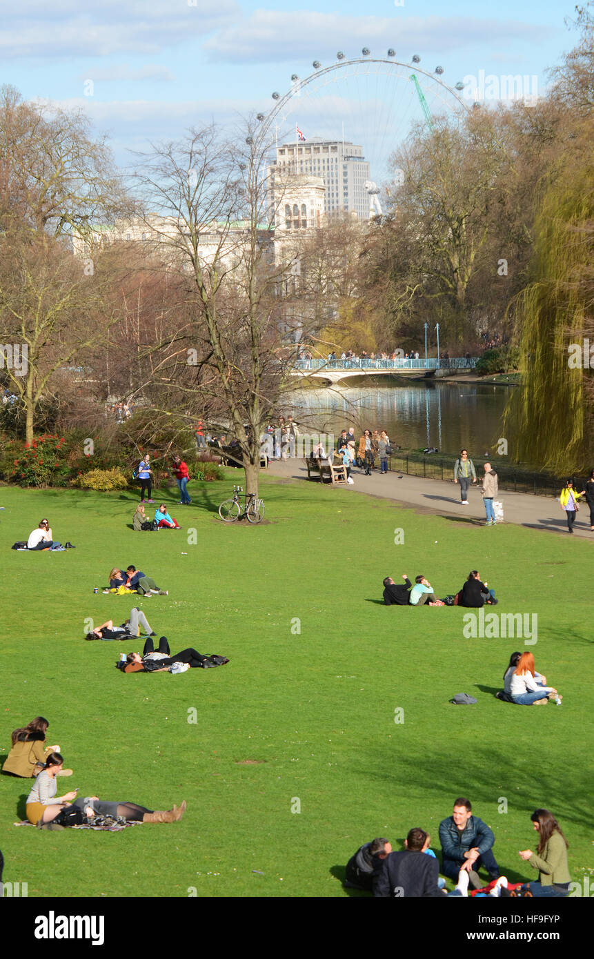 Turisti che si godono una soleggiata giornata di marzo in St James Park con delle Guardie a Cavallo e il London Eye al di là Foto Stock