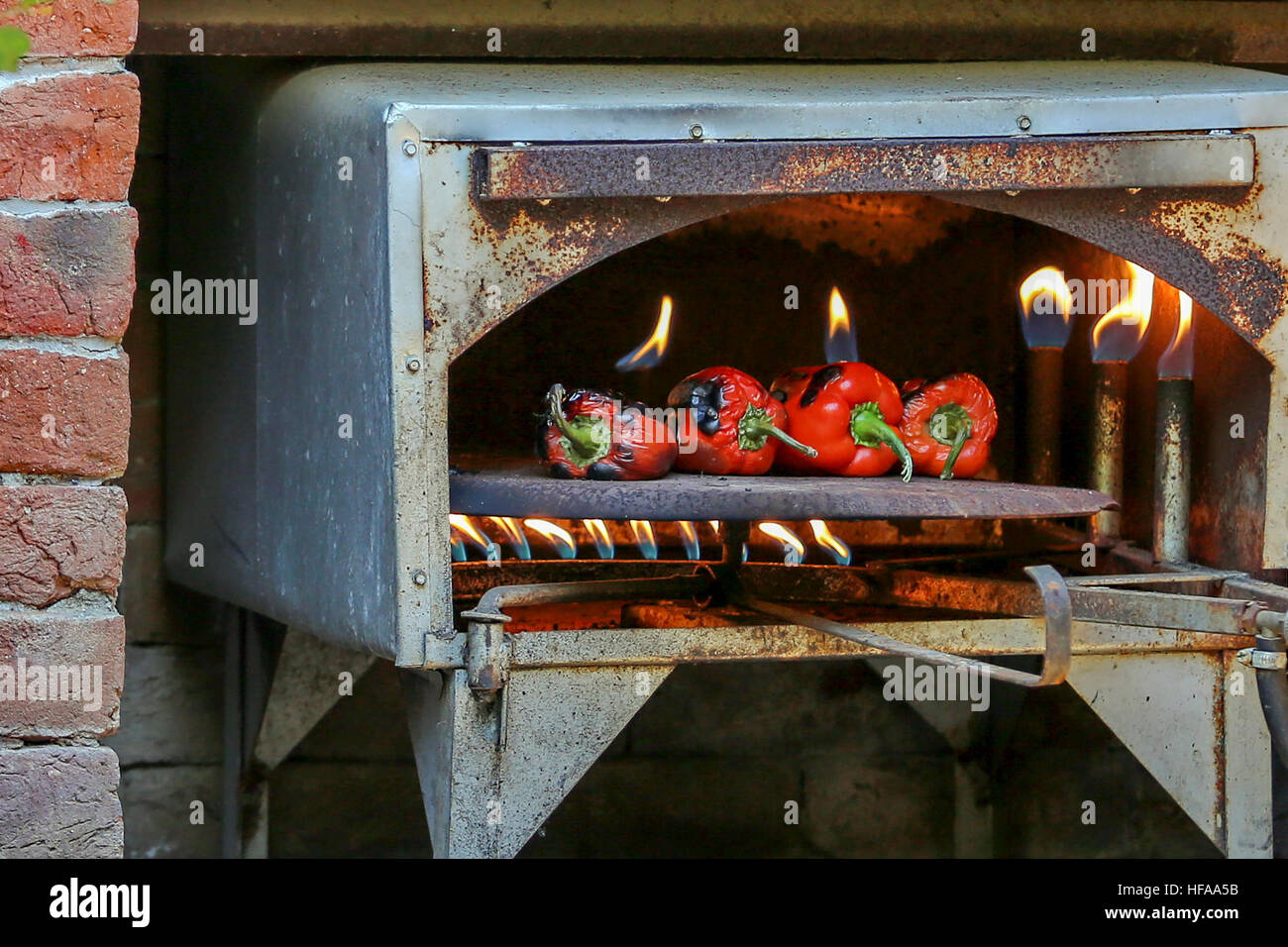 Peperoni rossi in una fiamma aperta forno a gas Foto Stock