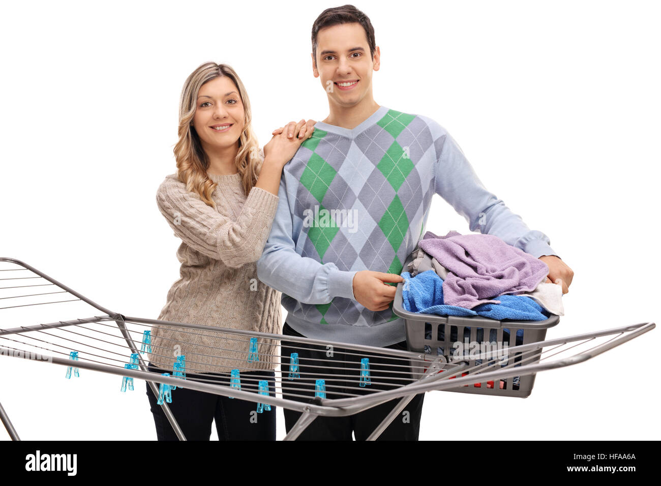 Coppia felice di stare dietro a un rack di abbigliamento essiccatore con l'uomo tenendo un cesto per la biancheria pieno di vestiti isolati su sfondo bianco Foto Stock
