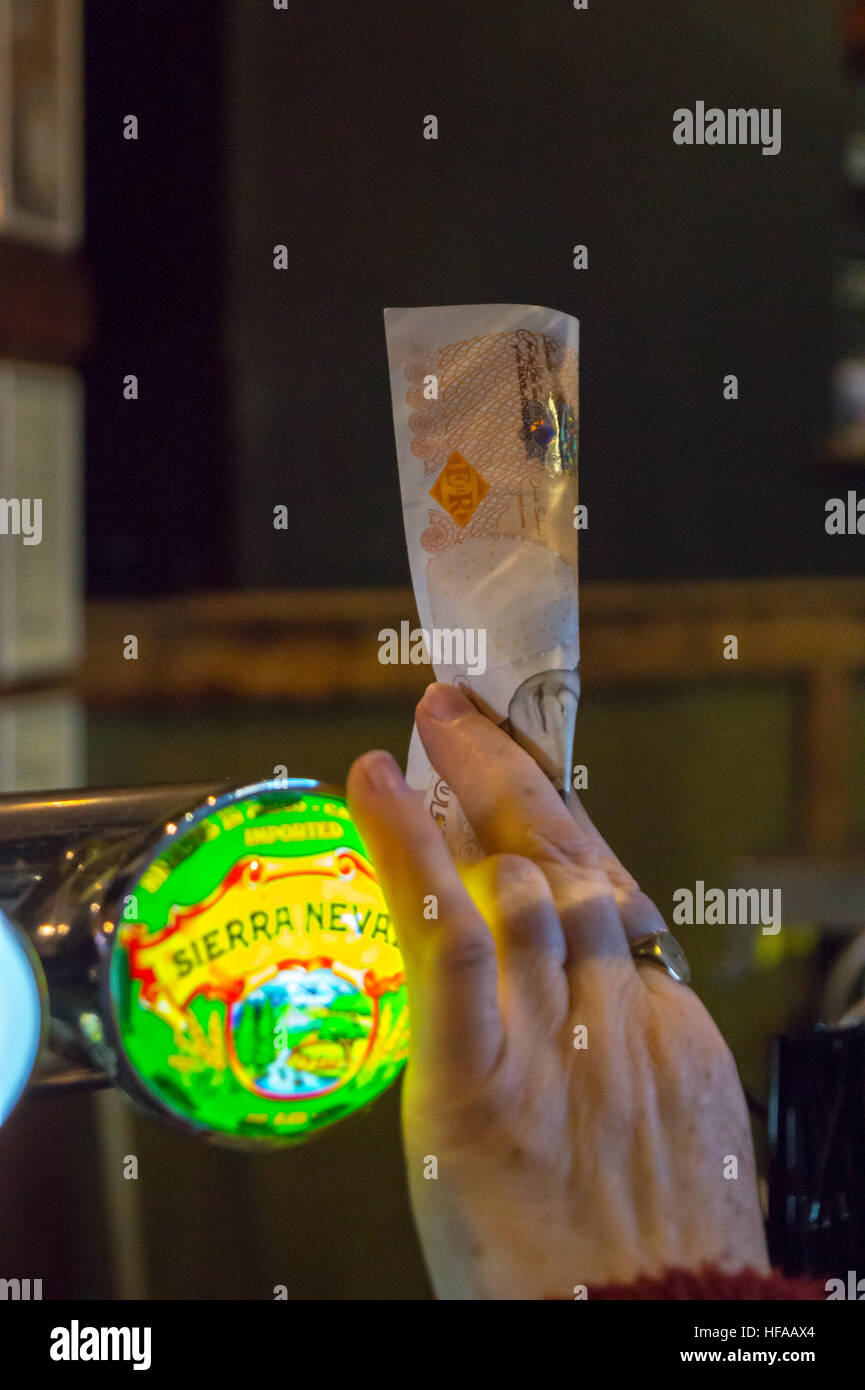 Una donna di mano azienda fino a 10£ Sterling nota in un bar Foto Stock