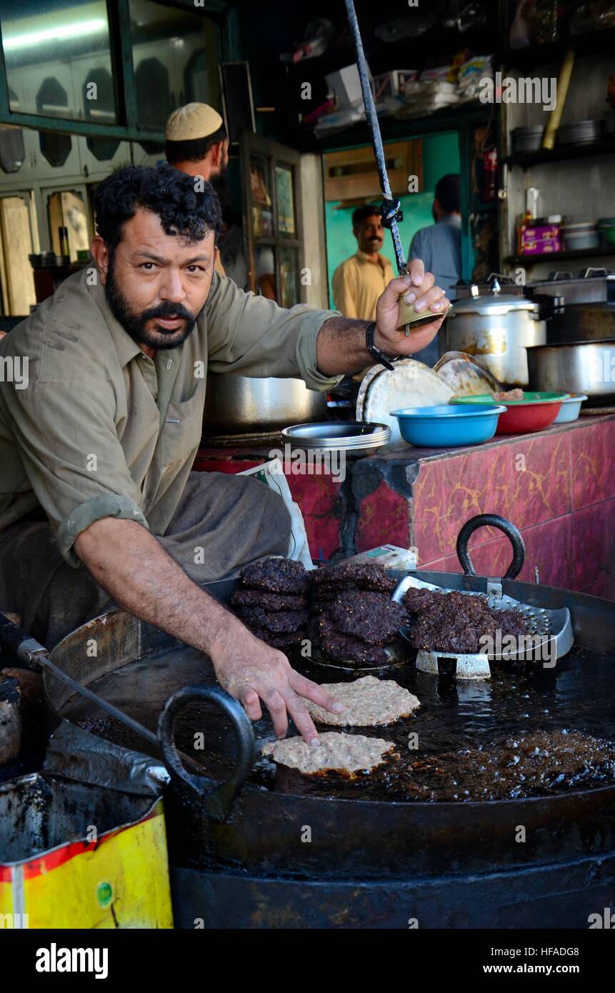 L uomo si prepara e patatine fritte chapli pakistano kebab piatto di carne in olio su una padella mentre il terminale voce squilla bell Gilgit Pakistan Foto Stock