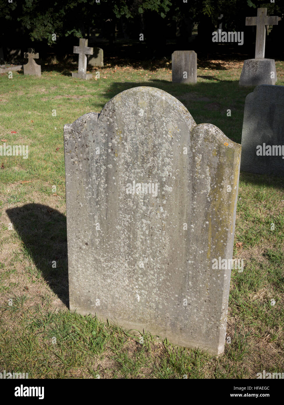Lastra piana lapide con sommità arrotondata design con headstone attraversa in background Foto Stock