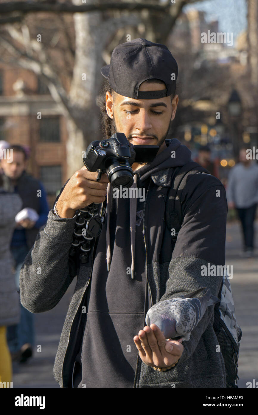 Foto di un uomo prendendo un selfie di se stesso mentre si alimenta un piccione in Washington Square Park nel Greenwich Village di New York City Foto Stock