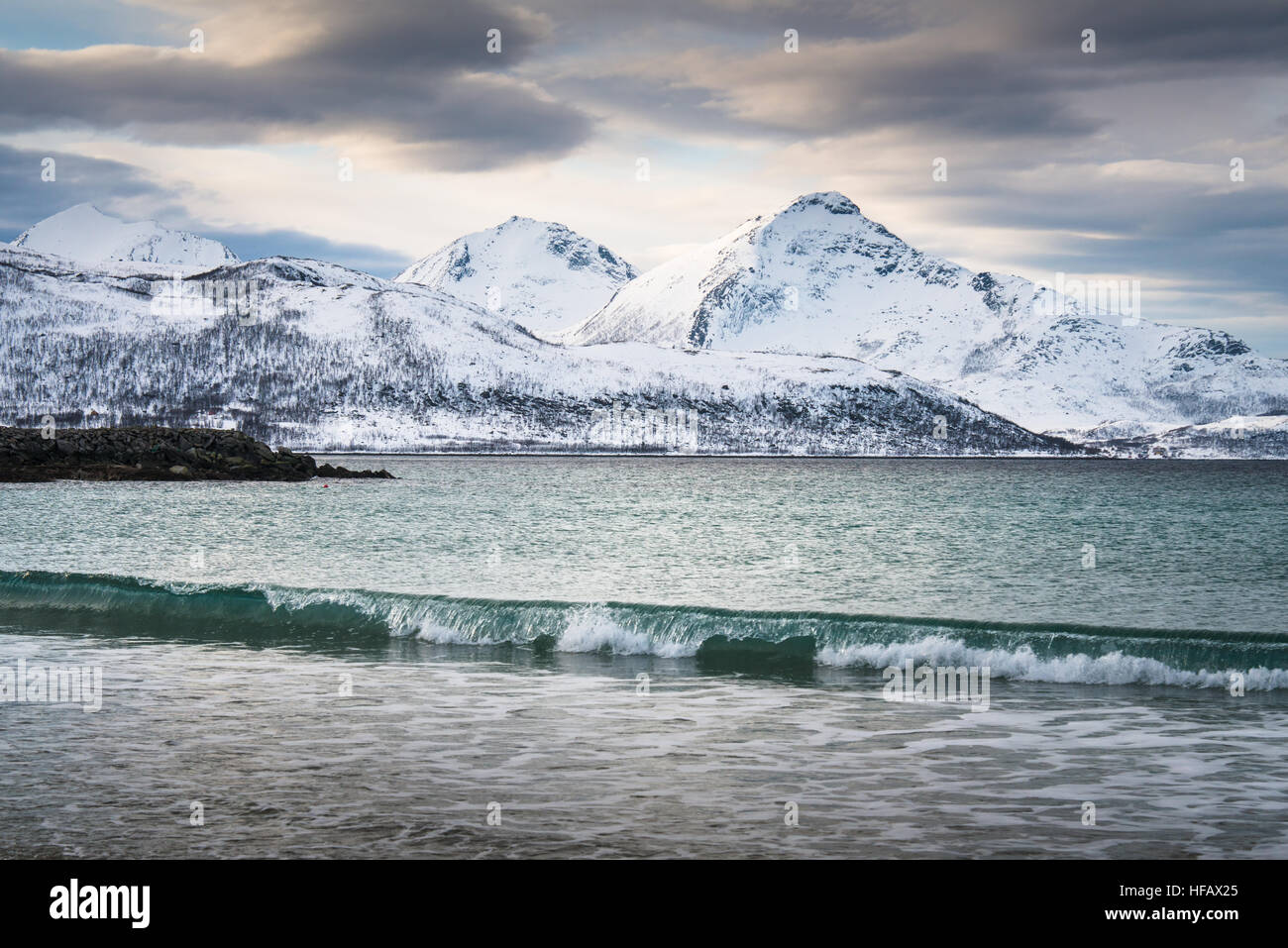 Onde del mare a freddo con cime innevate sullo sfondo Tromso, Norvegia Foto Stock