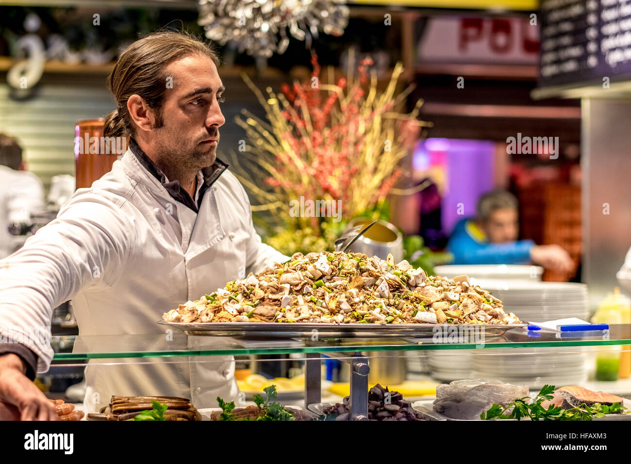 Un uomo spagnolo prepara deliziose tapas a base di pesce presso un ristorante cafe nel mercato La Boqueria, Barcellona Spagna. Foto Stock