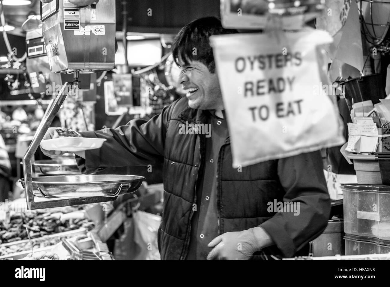 Un uomo spagnolo serve ostriche fresche pronto a mangiare da uno stallo in un mercato all'aperto a Barcellona Foto Stock