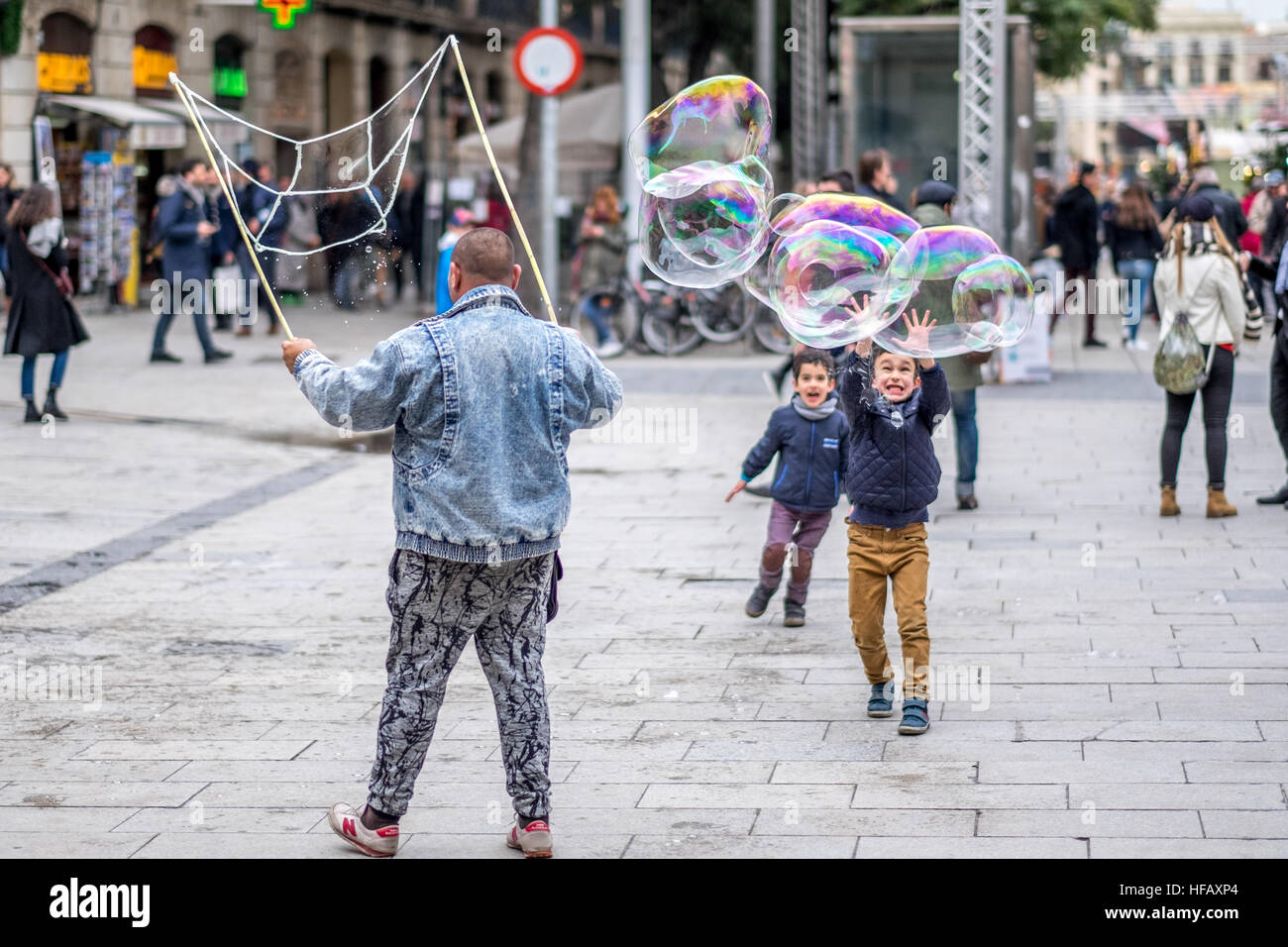 I ragazzi giocare con enormi bolle di sapone per le strade di Spagna sorriso jump eseguire il gioco Foto Stock