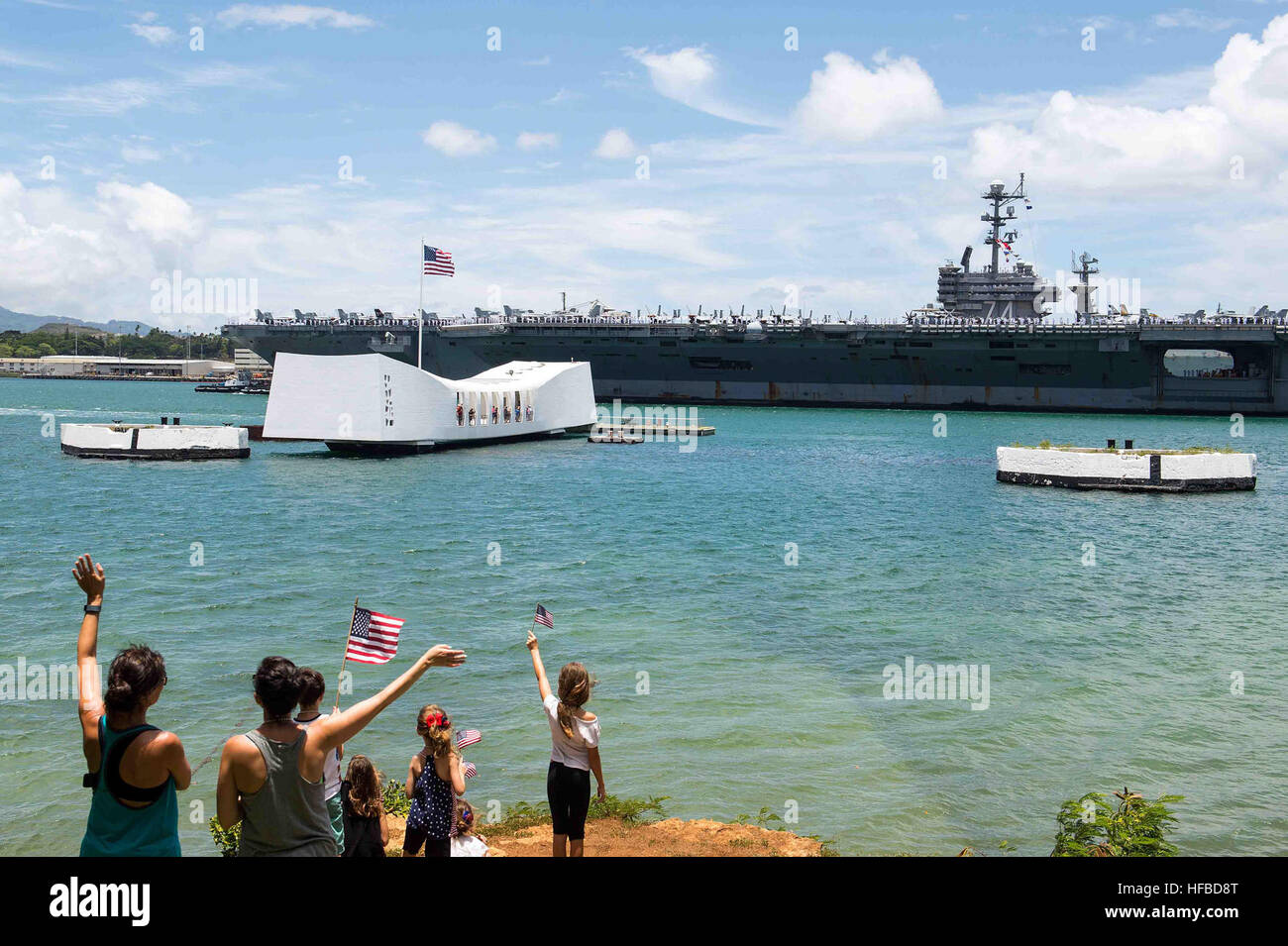 PEARL HARBOR (29 giugno 2016) le famiglie come onda la Nimitz-class portaerei USS John C. Stennis (CVN 74) rende onore a USS Arizona Memorial come la nave si prepara per ormeggiare in corrispondenza della giunzione base navale Pearl Harbor-Hickam a partecipare a bordo della Pacific 2016. Venti-sei nazioni, più di 40 navi e sottomarini, più di 200 aerei e 25.000 personale partecipano RIMPAC dal 30 giugno al 4 agosto, in e intorno alle Isole Hawaii e la California del Sud. Il più grande del mondo marittimo internazionale esercitazione RIMPAC offre una singolare opportunità di formazione che aiuta i partecipanti a fo Foto Stock