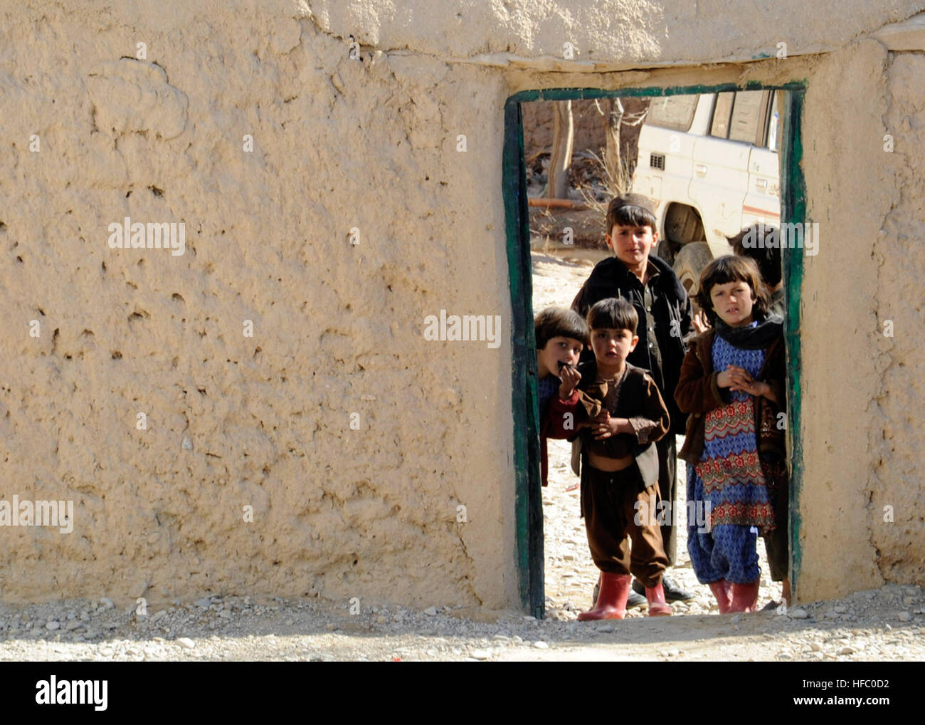 Bambini peek attraverso una porta al di fuori di una shura nel distretto di Gizab, provincia di Uruzgan, Afghanistan, gen. 18. La shura era tenuto a distribuire district gli stipendi degli insegnanti e manuali educativi. Distretto Gizab insegnante il giorno di paga 120118-N-MIA805-076 Foto Stock
