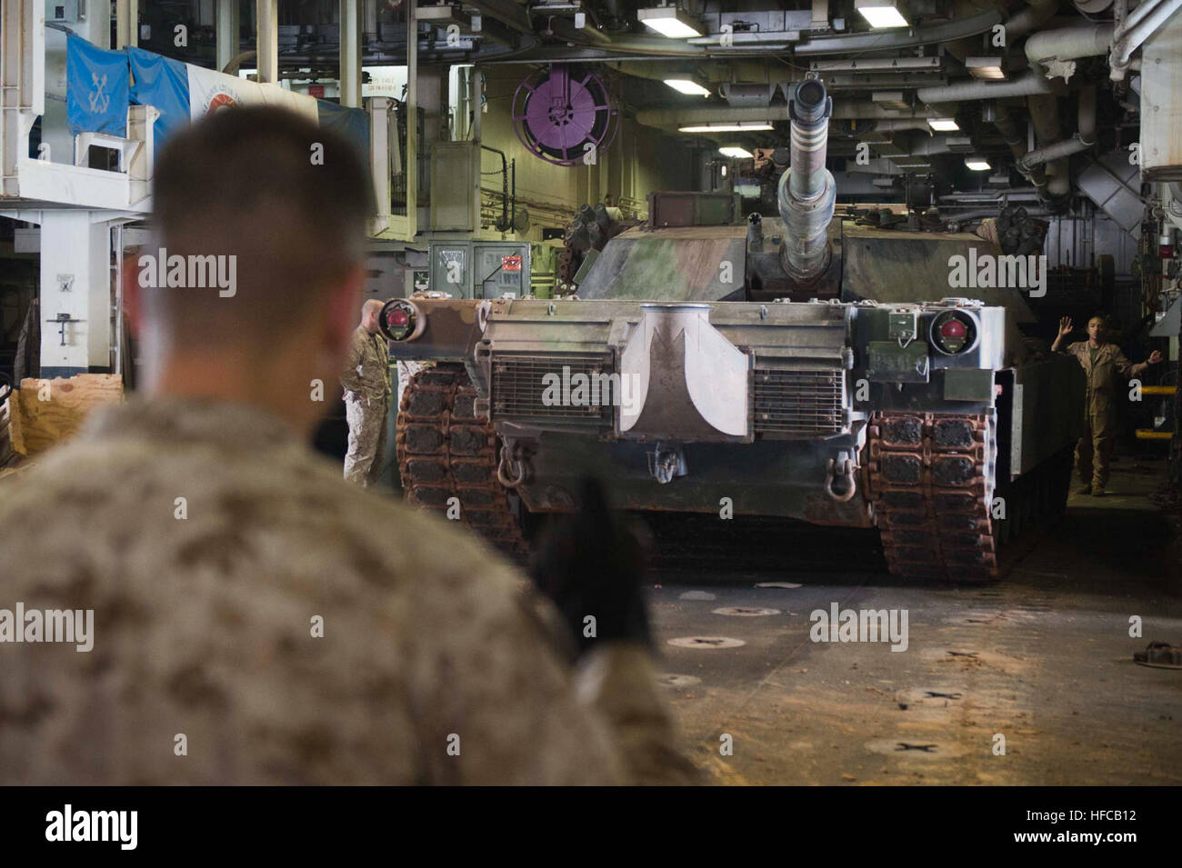 Un U.S. Marine assegnato alla XXIV Expeditonary marino unità (MEU) guide un M1A1 Abrams serbatoio in un hangar bay a bordo l'assalto anfibio nave USS Iwo Jima (LHD 7) nel Mar Arabico Luglio 9, 2012. Iwo Jima e il ventiquattresimo MEU sono state distribuite per gli Stati Uniti Quinta Flotta area di responsabilità condurre le operazioni di sicurezza marittima e di protezione del teatro gli sforzi di cooperazione. (U.S. Foto di Marina di Massa Specialista comunicazione marinaio apprendista Scott Youngblood/RILASCIATO) le operazioni di sicurezza marittima 120709-N-QM601-046 Foto Stock