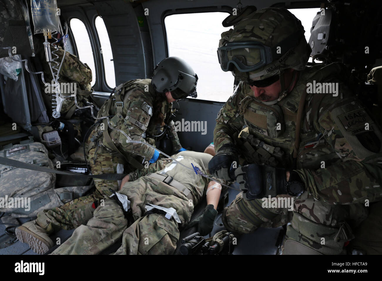 Stati Uniti Esercito il Mag. Giacobbe MacGregor (destra) certificata infermiere anestesista per la 541st in avanti il team chirurgico (airborne), prepara una sacca IV mentre il personale Sgt. Jolene Davis (inginocchiato a sinistra) volo medic per C Company, "Northstar Dustoff,' 2-211esimo reggimento di aviazione (Air Ambulance), esegue una valutazione di incidenti su una simulazione di incidenti, U.S. Operazioni navali specialista in seconda classe Niretzy Hill, PRT tactical operations center watchstander, mentre in volo su un UH-60 Black Hawk medevac elicottero durante l evacuazione medica formazione su FOB Farah, Gen 9. PRT Farah è coordinato con C Company, "Northstar Dusto Foto Stock