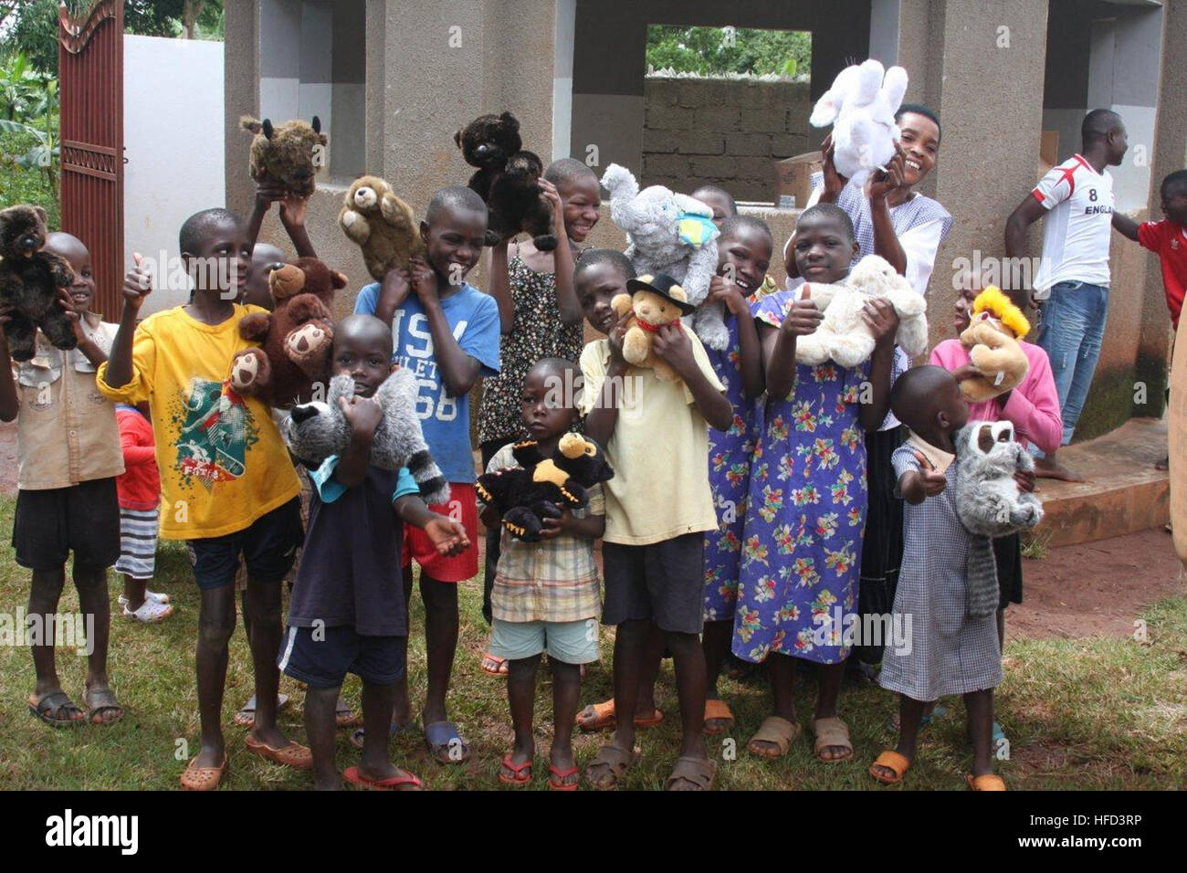 I membri del servizio della Combined Joint Task Force-Horn of Africa presso la sede operativa di Forward Kenyasi consegnano animali di peluche donati ai bambini della Suubi Children's Home di Entebbe, Uganda, come parte dei continui sforzi di volontariato. Foto Stock