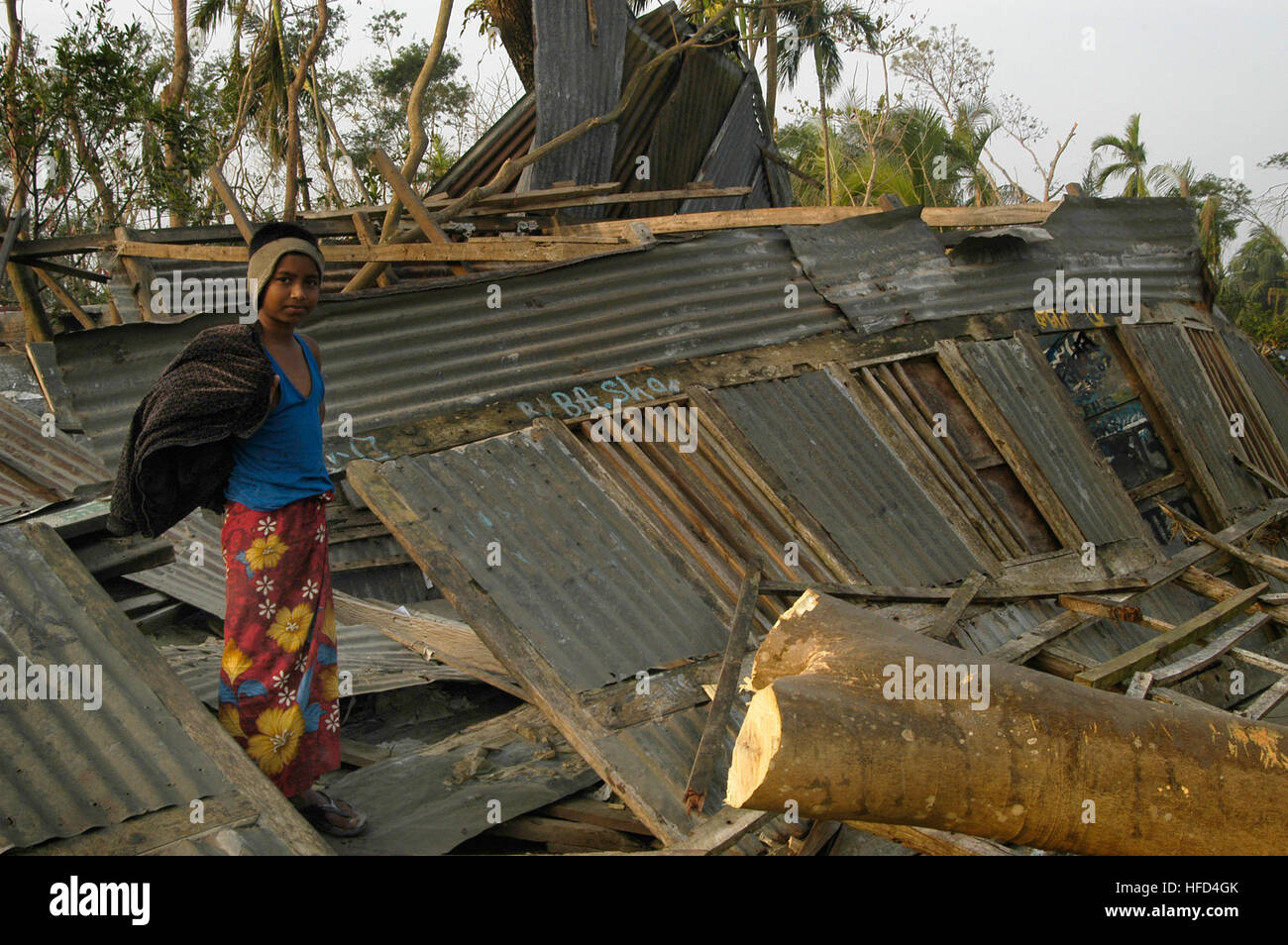 071202-N-5642P-186 SARANKHOLA, Bangladesh (2 dicembre 2007) un bambino di Sarankhola, il Bangladesh si erge al di fuori della sua casa demolita. L'assalto anfibio nave USS Kearsarge (LHD 3) e ha avviato 22 Marine Expeditionary Unit (Operazioni speciali in grado) sono in conduzione assistenza umanitaria/i soccorsi in risposta al governo del Bangladesh di richiesta di assistenza dopo il ciclone tropicale Sidr hanno colpito i loro costa meridionale nov. 15. La tempesta ha causato la morte di oltre 3 mila persone e ha lasciato centinaia di migliaia di senzatetto. Il Dipartimento della Difesa di sforzo è parte di un più grande ONU Foto Stock