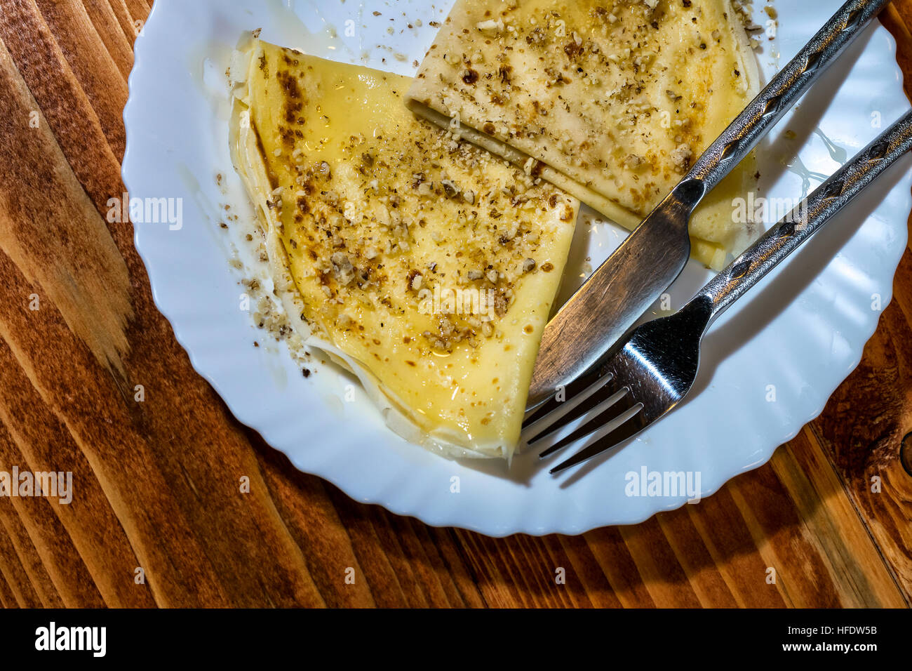 Crepes Pancake con miele e noci in una piastra su un tavolo di legno Foto Stock