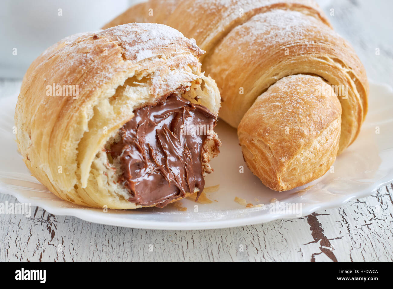 Croissant con cioccolato ripieno su bianco rustico sfondo di legno Foto Stock