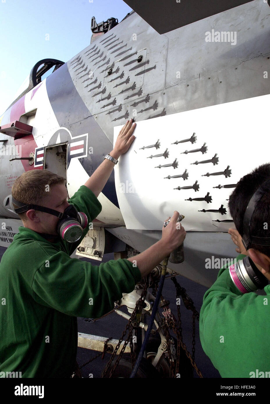 030529-N-0295M-005 Oceano Pacifico (29 maggio 2003) - Aviazione meccanico strutturale Airman apprendista Daniel Moore, sinistra e aviazione macchinista Mate 3° di classe Enrique Cresporodriguez, assegnato a Fighter Squadron due (VF-2) Controllo della Corrosione centro di lavoro, utilizzare una pistola a spruzzo di vernice bomb marcature sulla loro aeromobili. Questo sta a significare il numero di gocce di bomba che ha avuto luogo durante il ruolo squadronÕs nell Operazione Iraqi Freedom (OIF). VF-2 attualmente è di ritorno da una distribuzione con la Costellazione del Battle Group a sostegno di operazioni Southern Watch, Enduring Freedom e Iraqi Freedom. Stati Uniti Nav Foto Stock