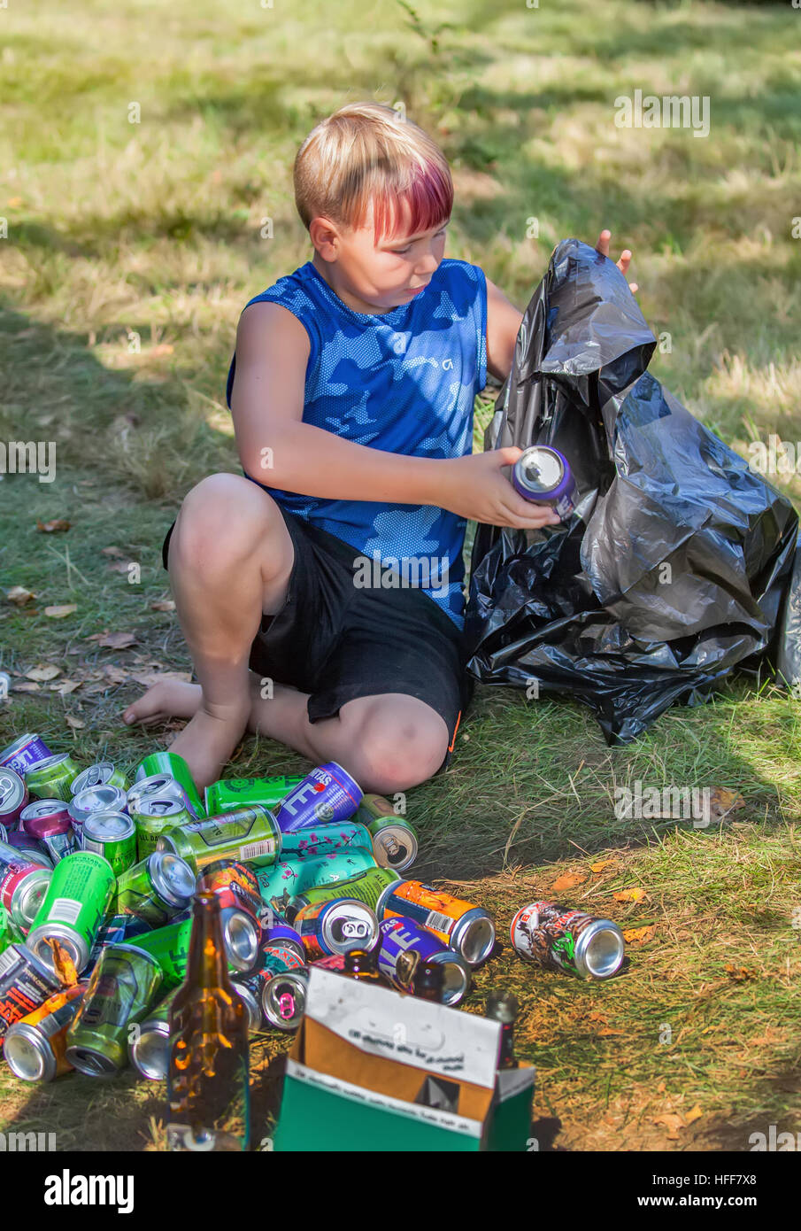 Un ragazzo di circa dieci anni raccoglie lattine e bottiglie in un sacco nero per il riciclaggio nel Vermont, USA. Foto Stock