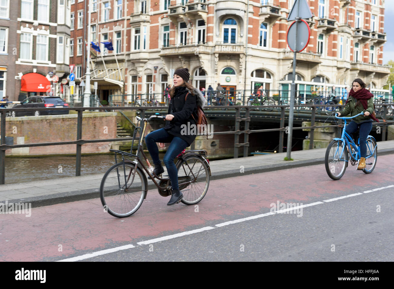 Due femmina ciclisti sulla strada a Amsterdam, Olanda, Paesi Bassi. Vi è di circa un milione di biciclette. Foto Stock