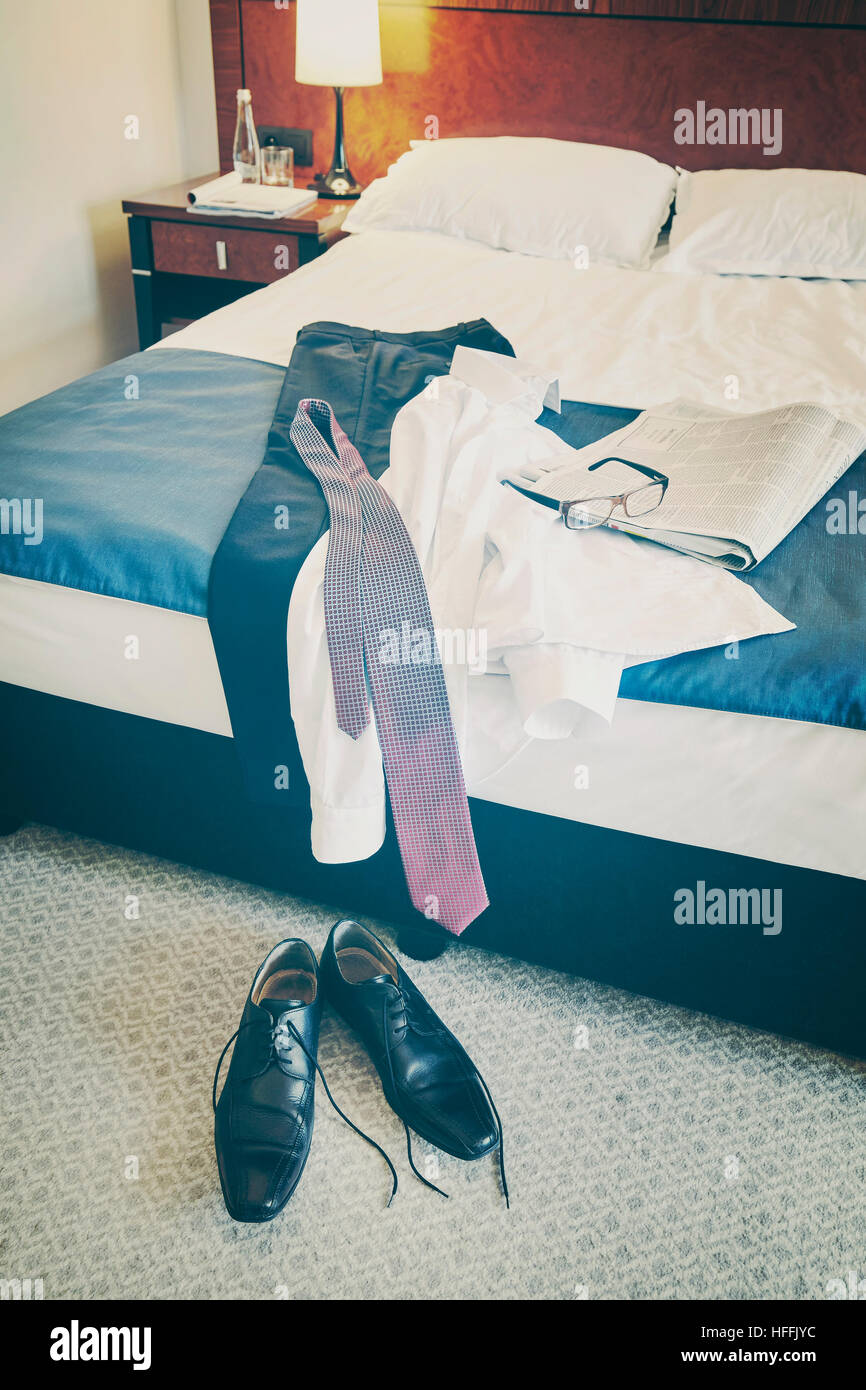 Vintage tonica maschio nero scarpe e vestiti in una camera di hotel bed. Foto Stock