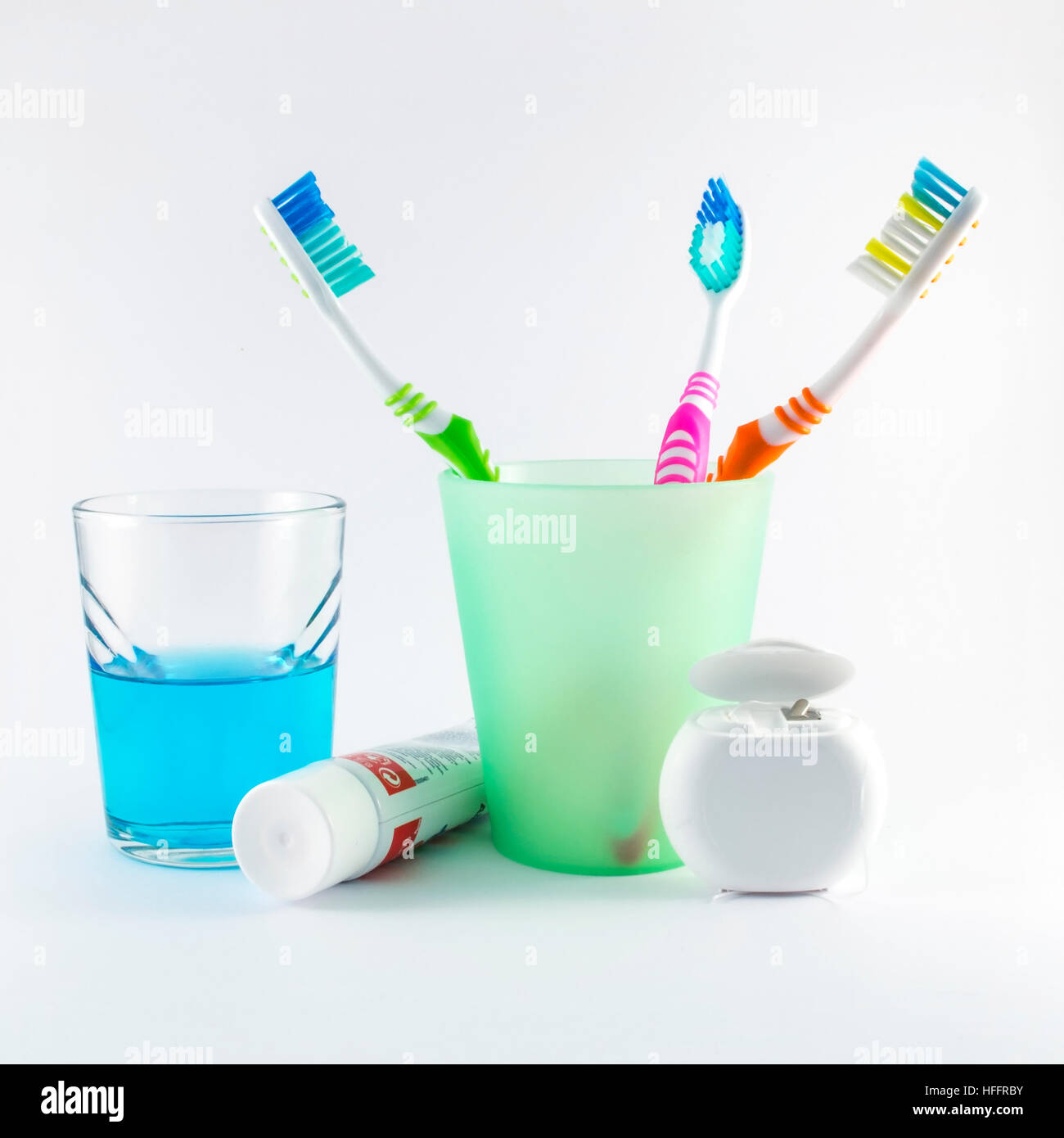 Gli spazzolini da denti multicolore, filo interdentale, dentifricio e collutorio su sfondo bianco Foto Stock