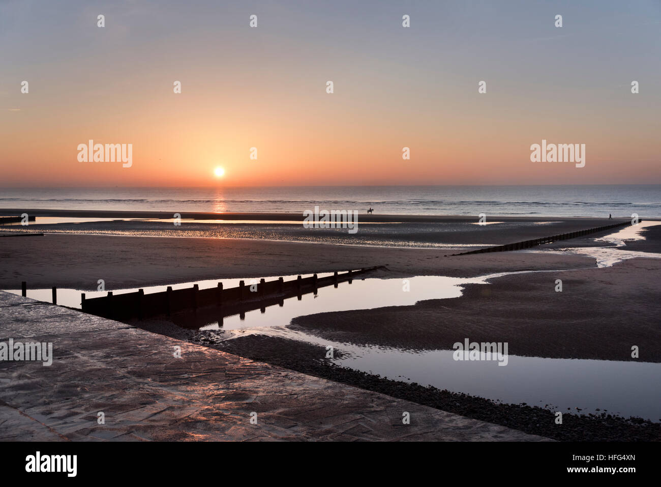 Tramonto in inverno oltre la stazione balneare di Cleveleys Lancashire, con horserider distanti sulla spiaggia Foto Stock
