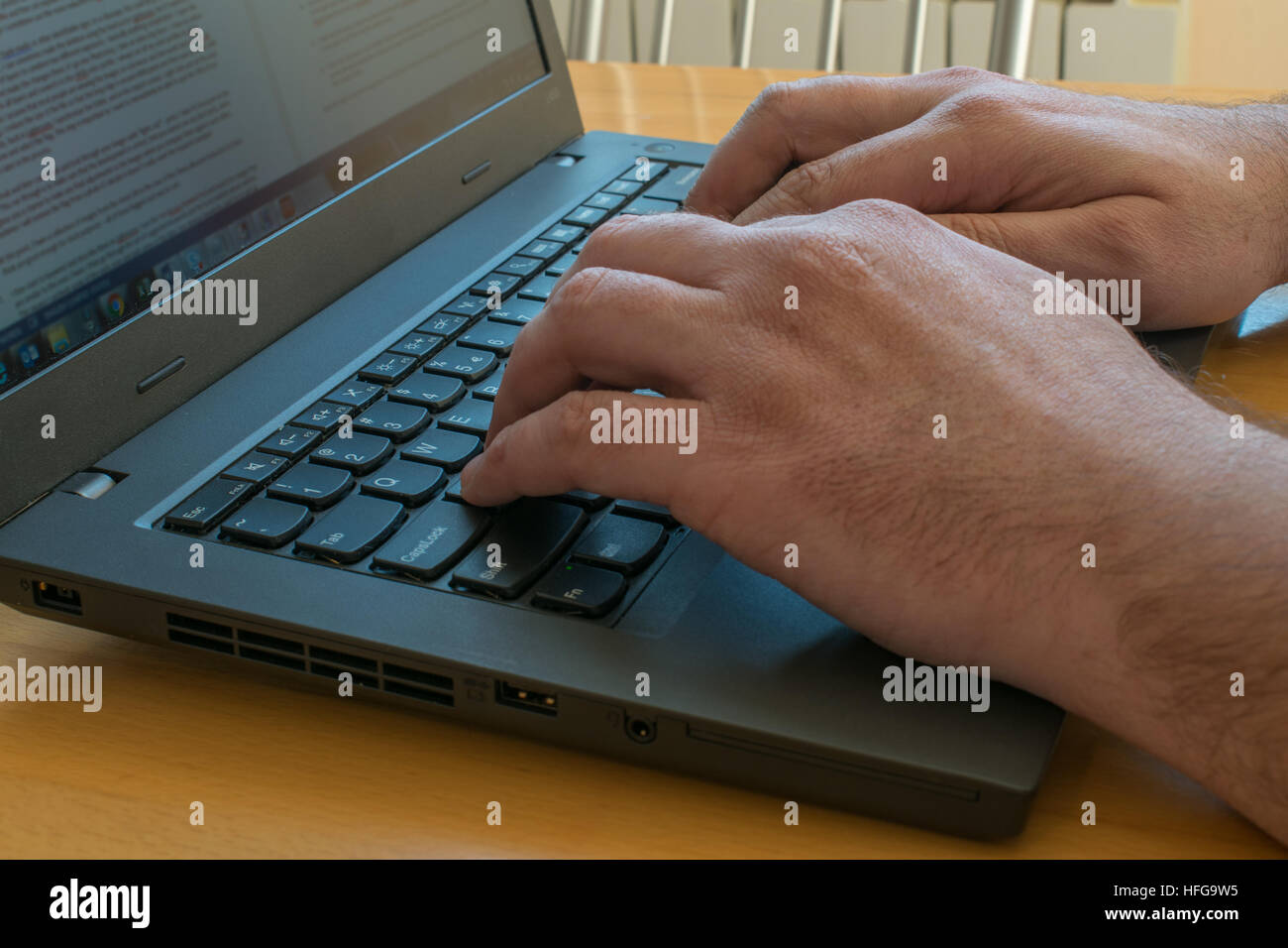 Vista laterale su laptop sulla scrivania con maschio mani vicino a digitare sulla tastiera Foto Stock