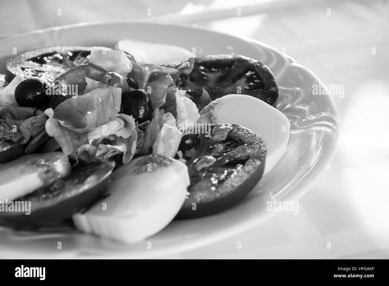 Insalata caprese con pomodori, mozzarella, insalata e condimento di olive al pesto su bianco. Vintage in bianco e nero Foto Stock