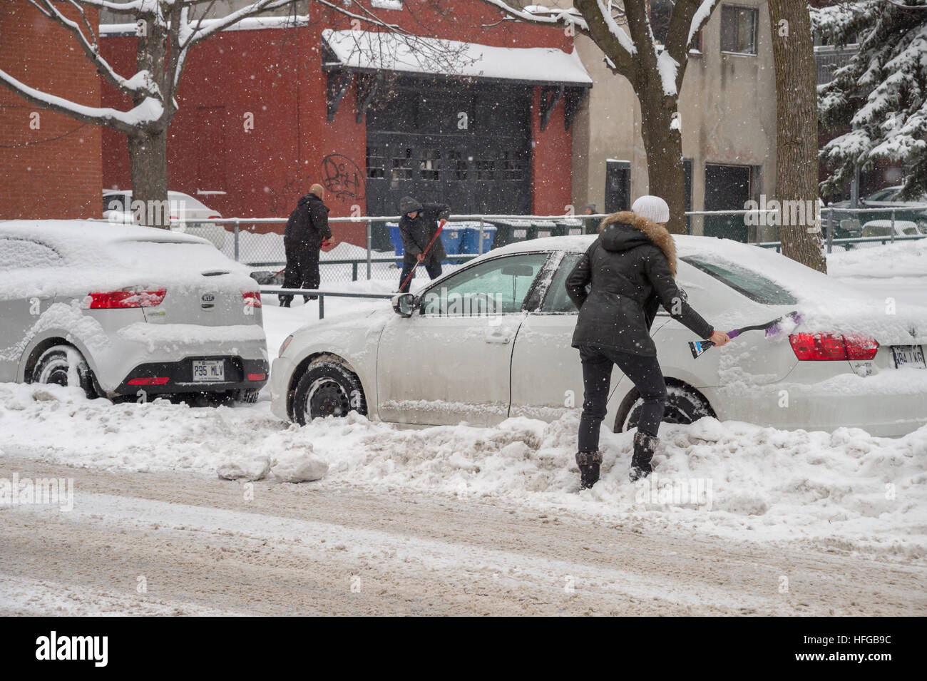 Montreal, CA - 12 dicembre 2016: pulizia donna la sua auto da neve durante una nevicata in inverno. Foto Stock