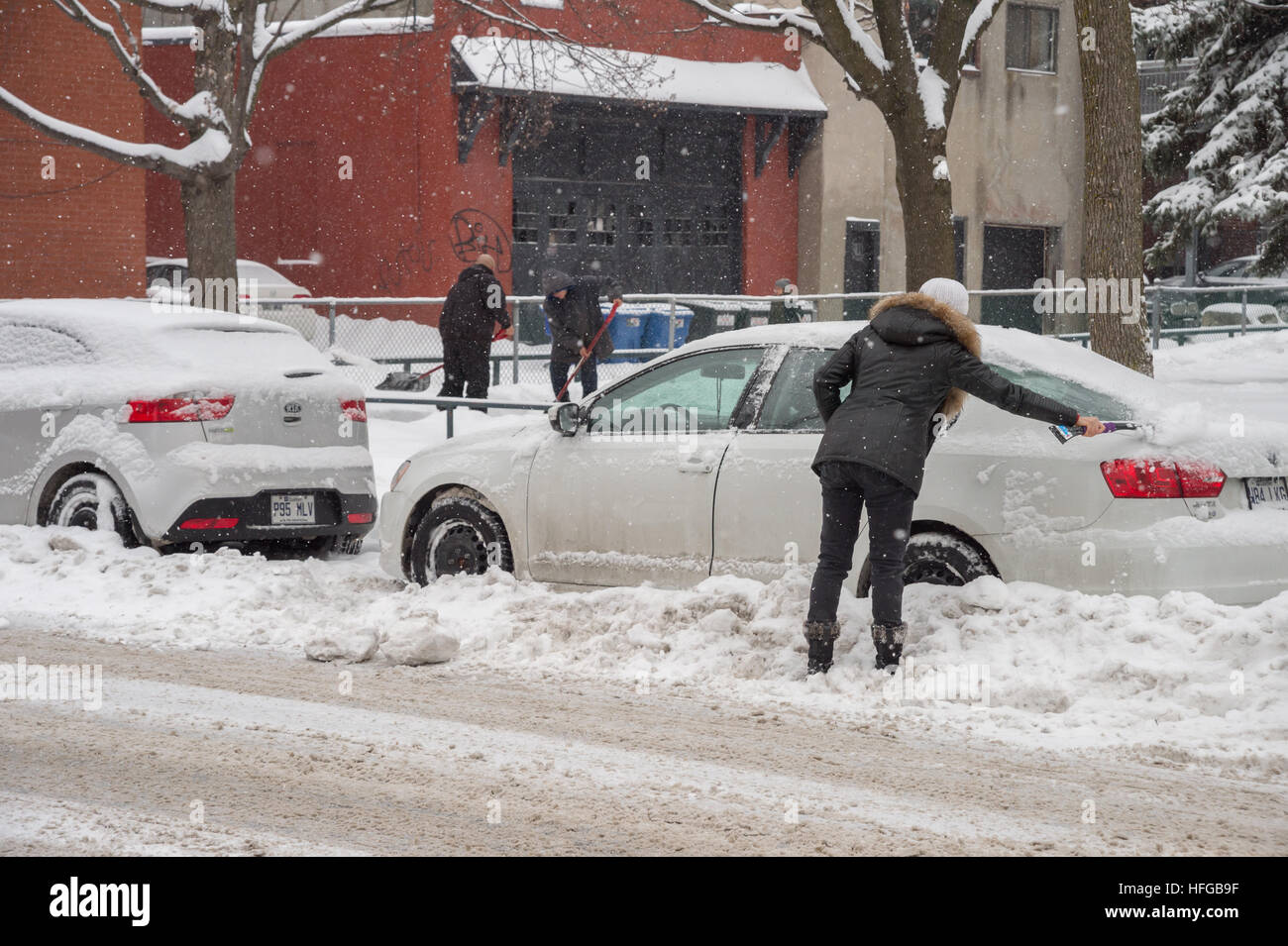 Montreal, CA - 12 dicembre 2016: pulizia donna la sua auto da neve durante una nevicata in inverno. Foto Stock