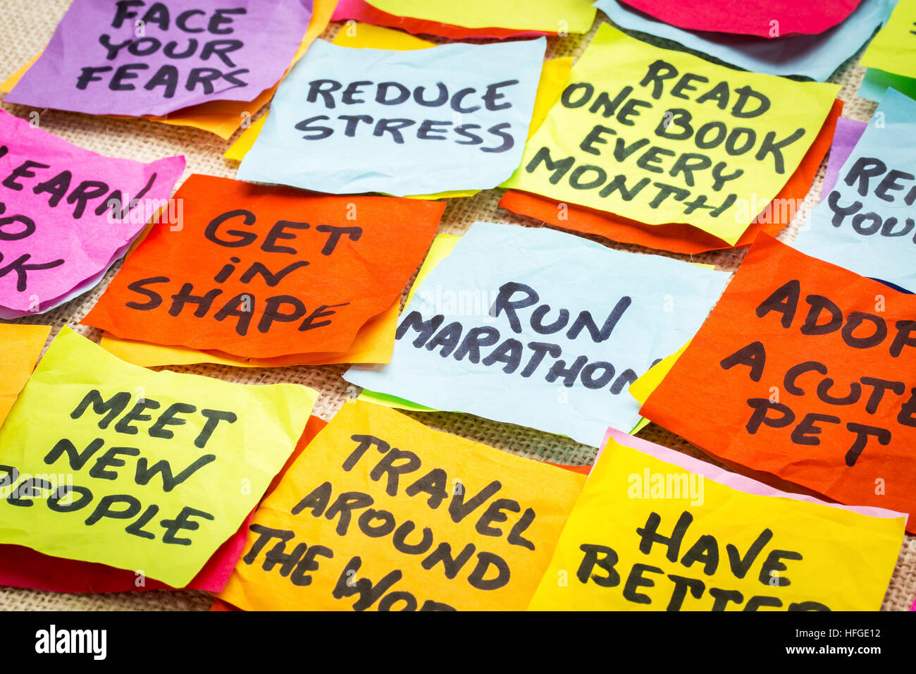 Realistiche e irrealistico nuovo anno obiettivi o risoluzioni - colorata sticky notes su tela Foto Stock