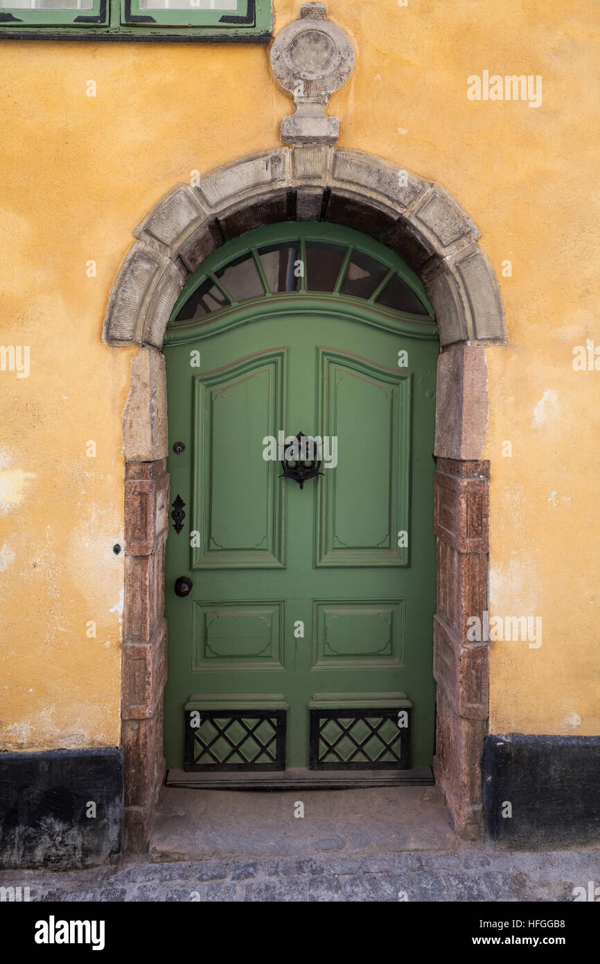 Il verde porta di legno in giallo antico muro, vecchia di Stoccolma, Svezia Foto Stock