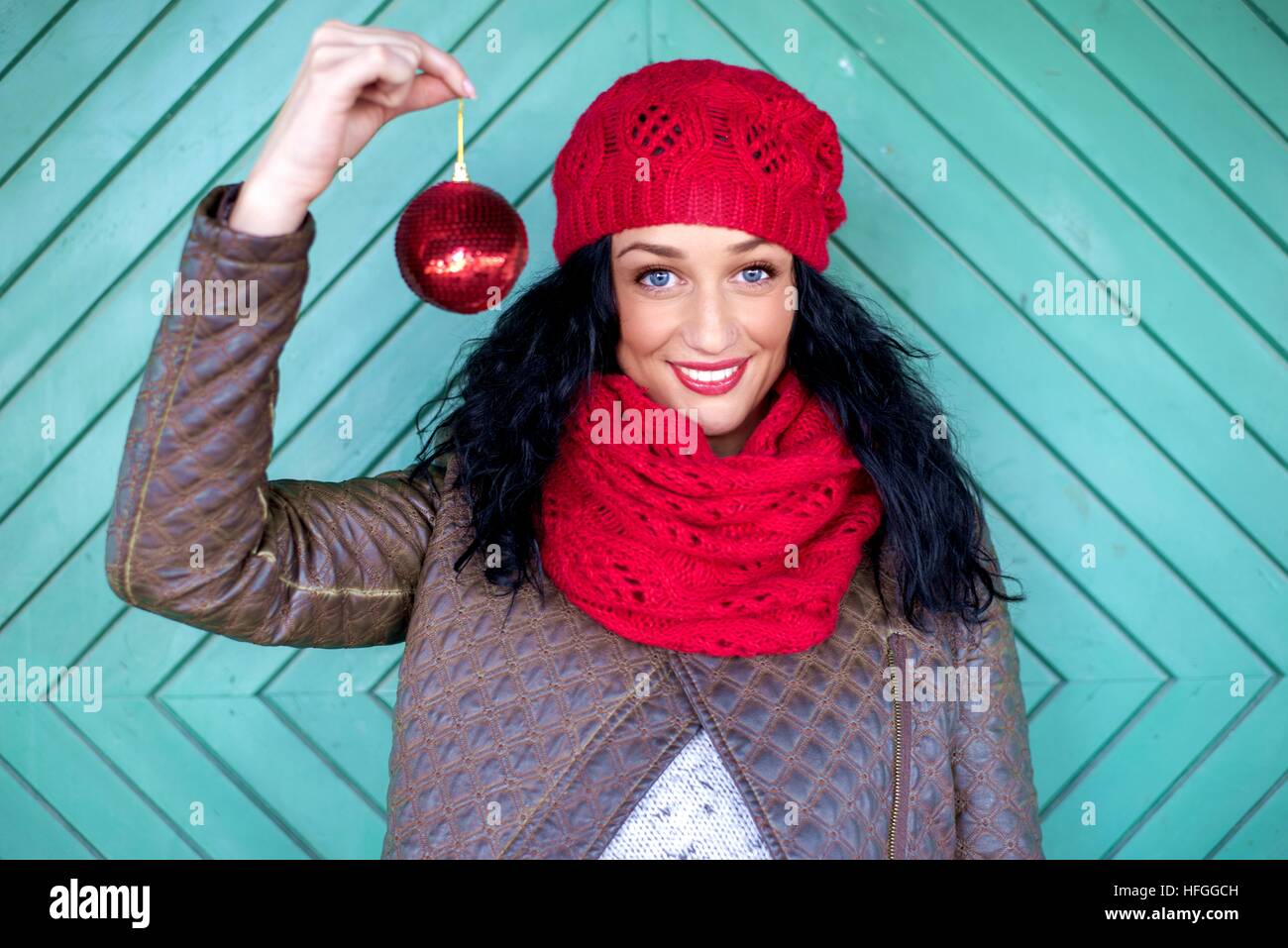 Giovane donna nel cappuccio rosso dalla vecchia porta con palla di Natale Foto Stock