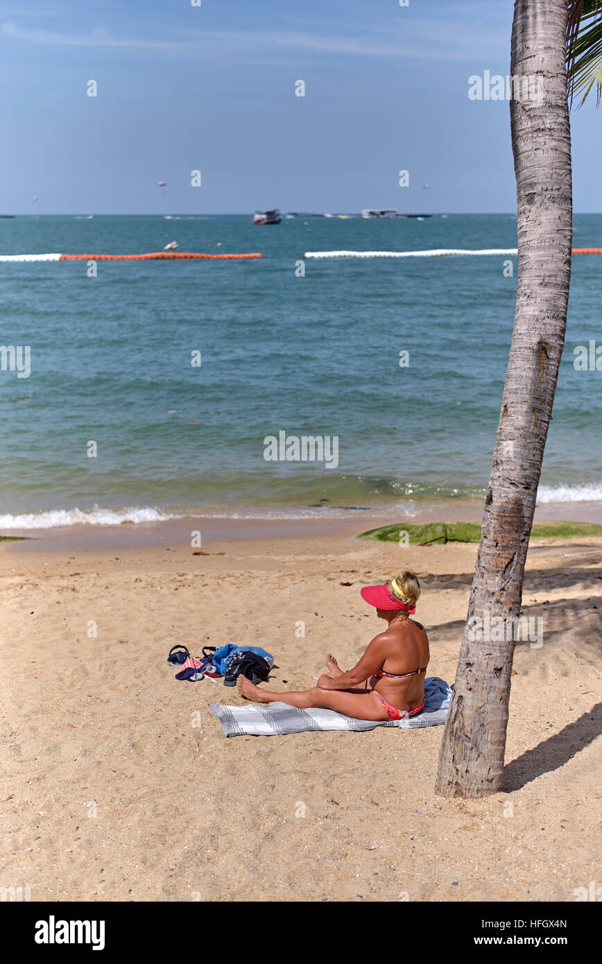 Donna sola spiaggia. Bikini rivestito femmina di sole su una spiaggia tropicale. Pattaya Thailandia S. E. Asia Foto Stock