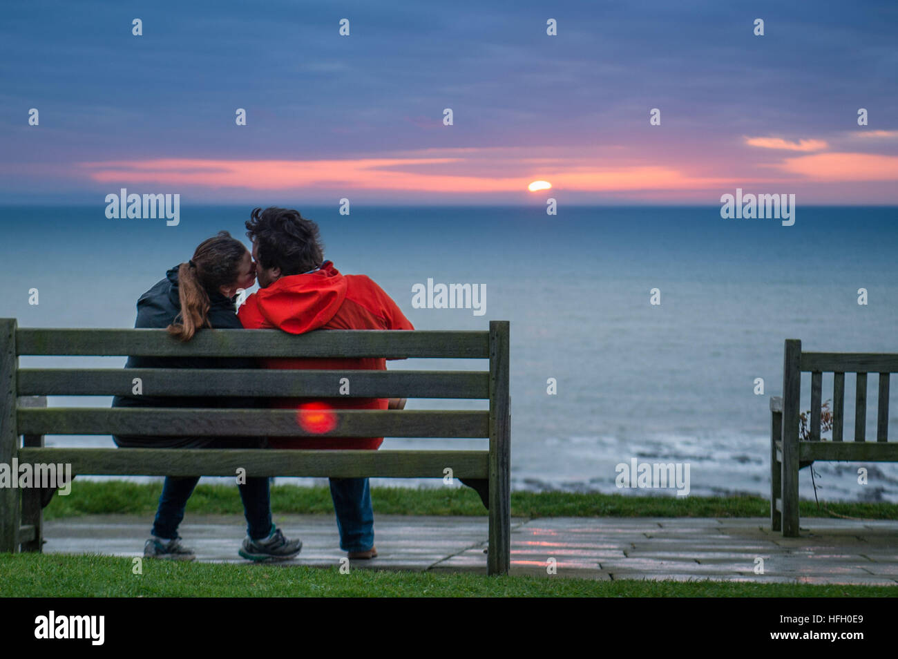 Aberystwyth Wales UK, venerdì 30 dicembre 2016 UK meteo: una giovane coppia  bacio come essi sul sedere insieme una panchina e guardare il tramonto in  un gap in nuvoloso nubi su Cardigan