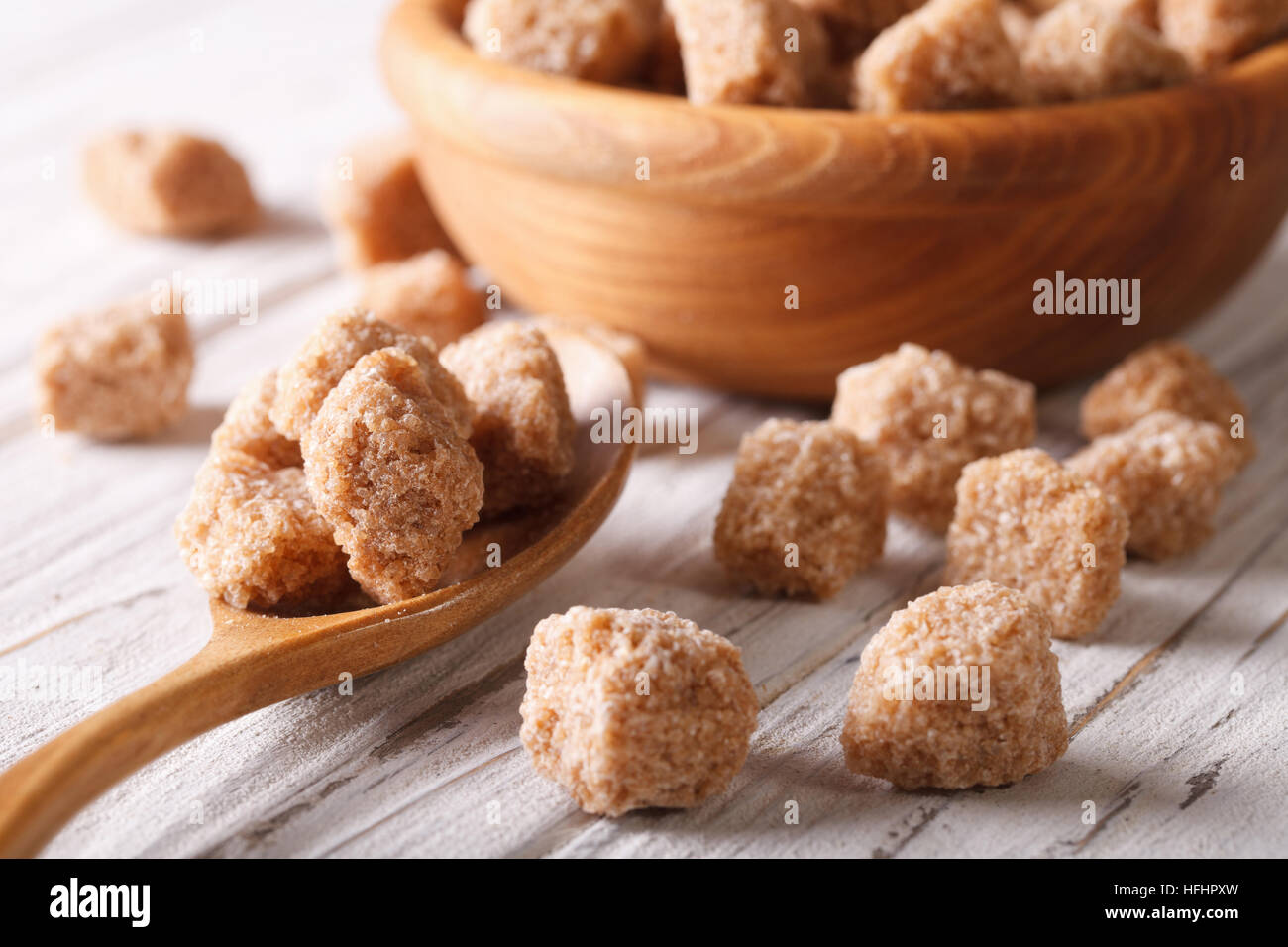 Grumo marrone zucchero di canna macro in un cucchiaio di legno sul tavolo orizzontale. Foto Stock