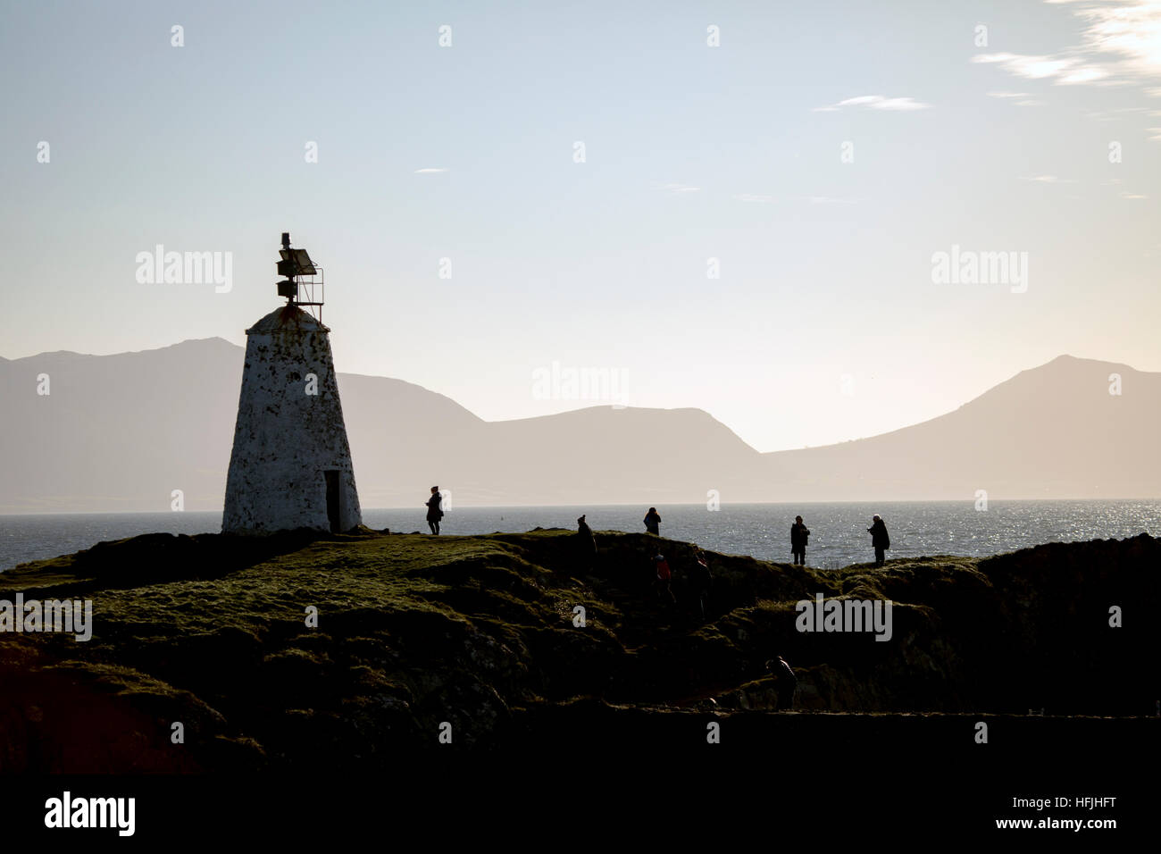 Visitatori godendo della vista sulla isola di Llanddwyn con Twr Bach lighthouse stagliano Llyn Peninsula mountain range Foto Stock