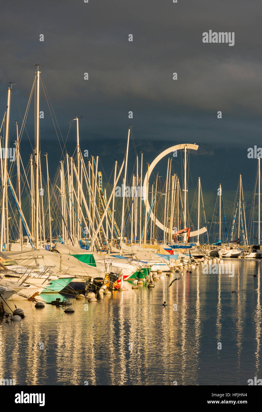 Eole banderuola e yacht riflettendo bassa serata sole estivo presso il porto di Ouchy, Losanna Vaud, Svizzera Foto Stock