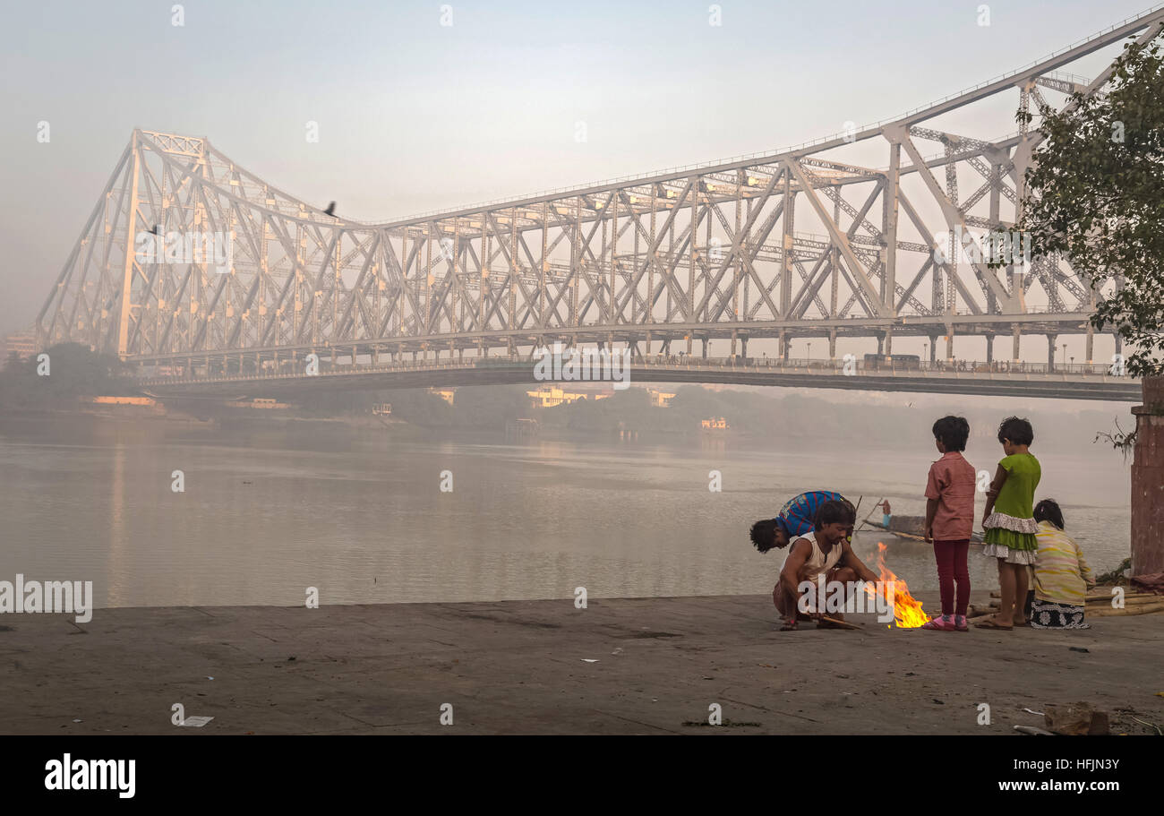 I bambini di strada tenete in caldo su un freddo inverno nebbiosa mattina a Mallick ghat vicino a quella di Howrah bridge presso la banca di fiume Hooghly. Foto Stock